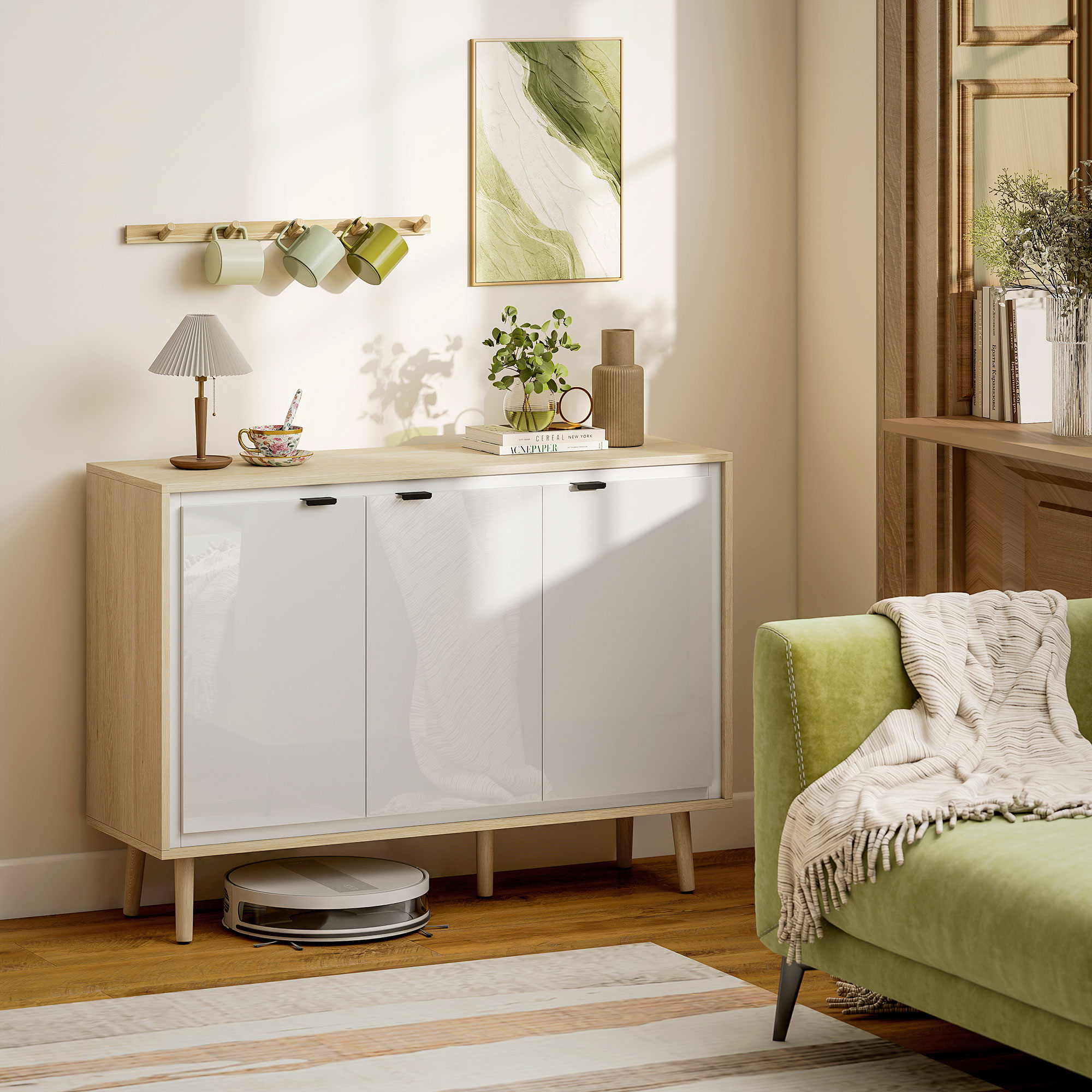 Una credenza con ante bianche, sopra lampada, tazza e decorazioni. Un divano con coperta e un robot aspirapolvere davanti.