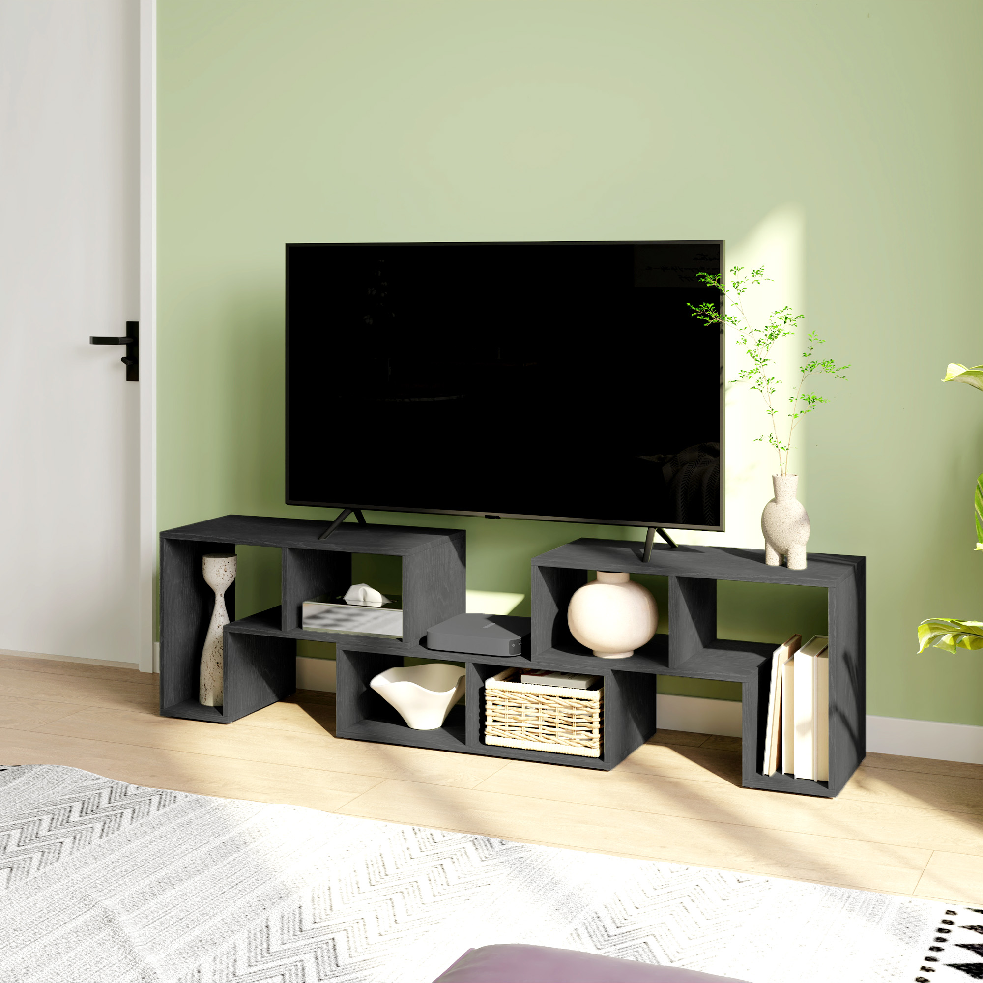 TV su mobile porta TV grigio scuro con decorazioni. Parete verde chiaro.