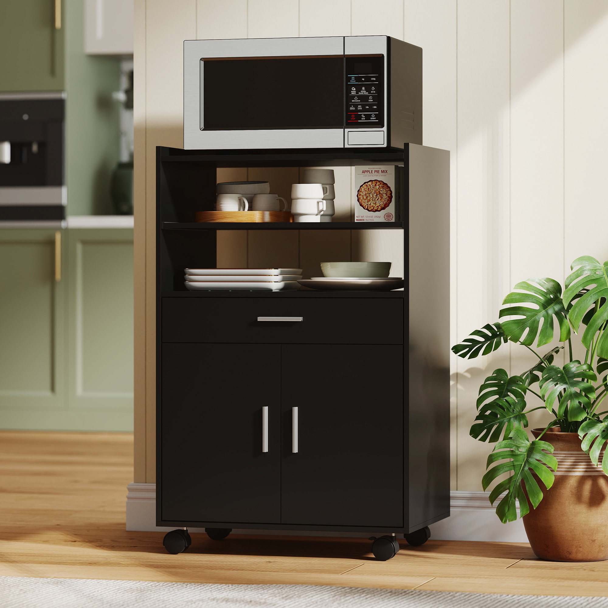 Un carrello da cucina nero con microonde, piatti e una pianta.