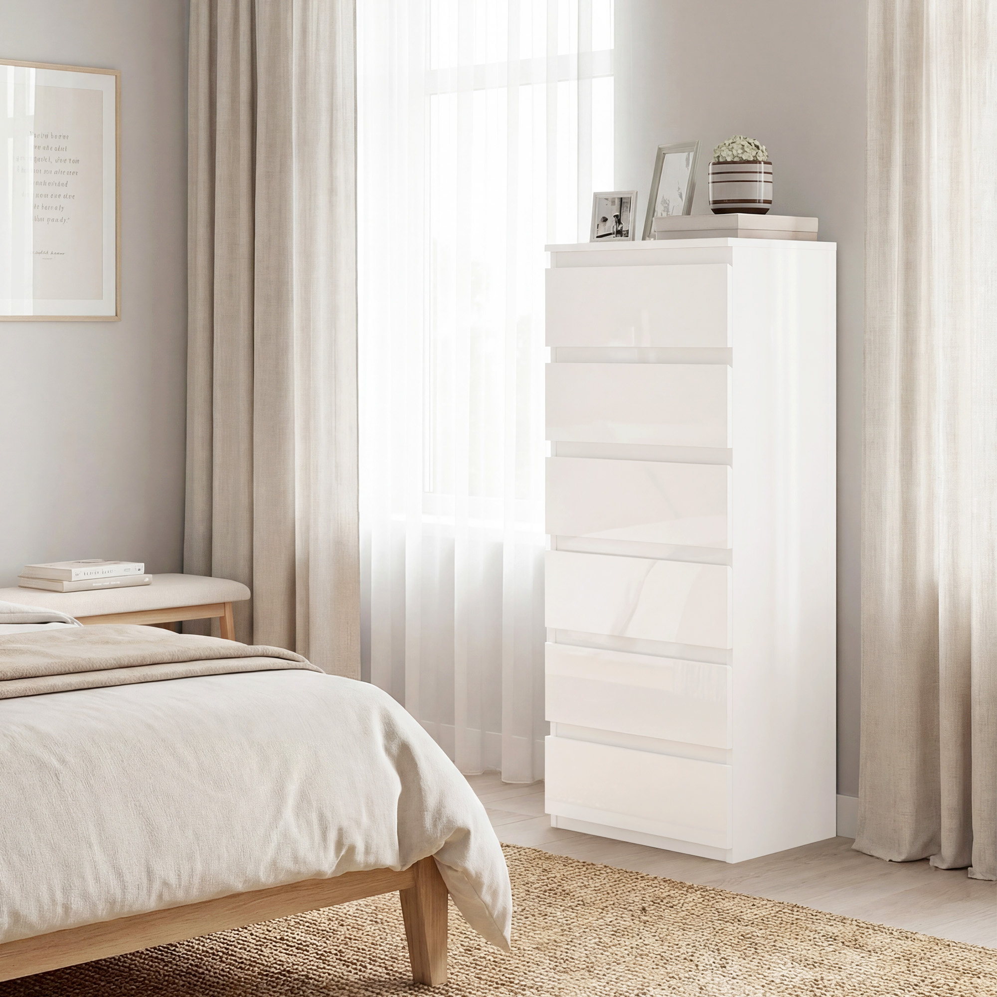 Un comò bianco accanto a un letto con biancheria da letto beige. Una finestra con tende sullo sfondo.