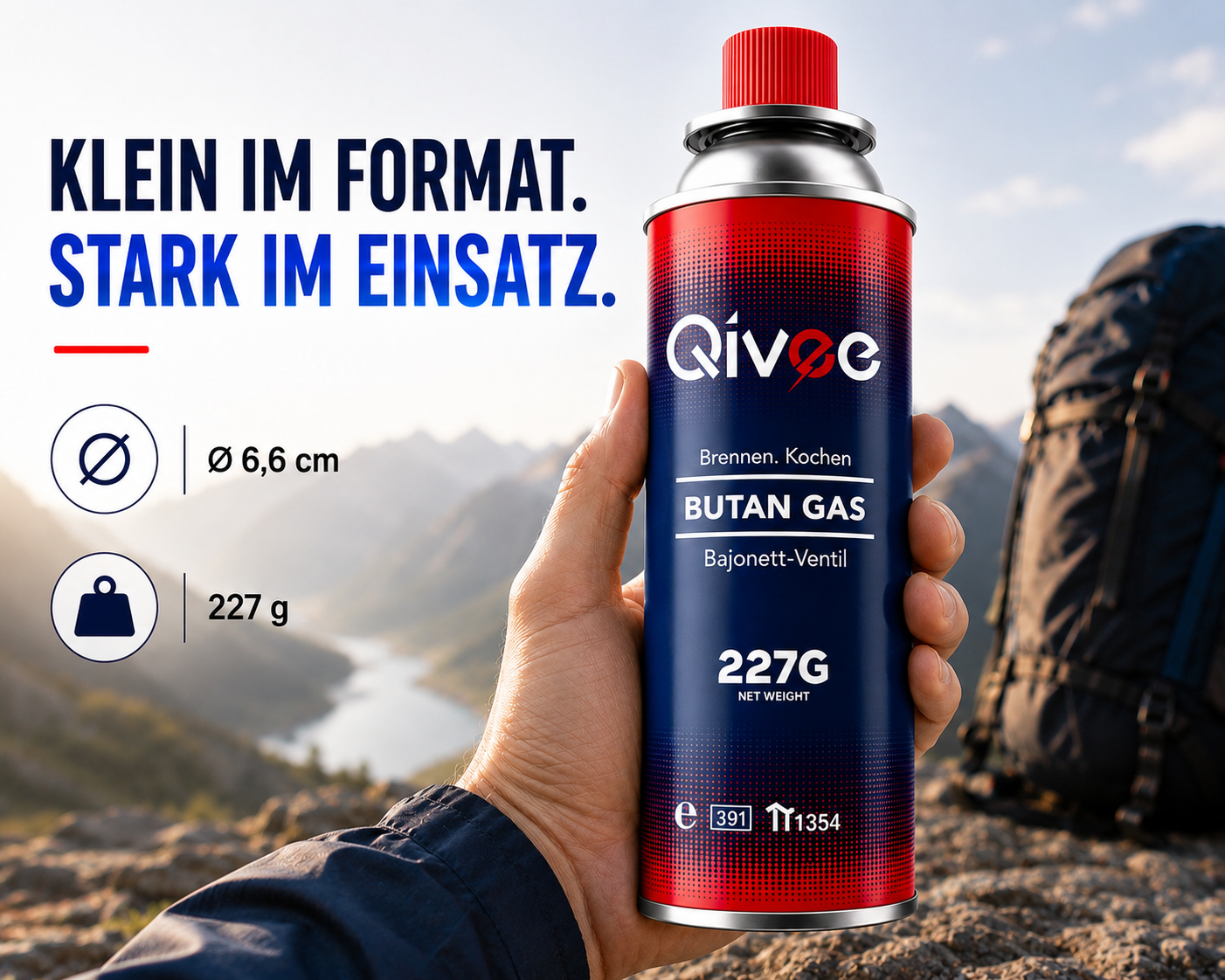 Eine Hand hält eine kleine blaue Gasdose mit rotem Deckel vor einer Berglandschaft.
