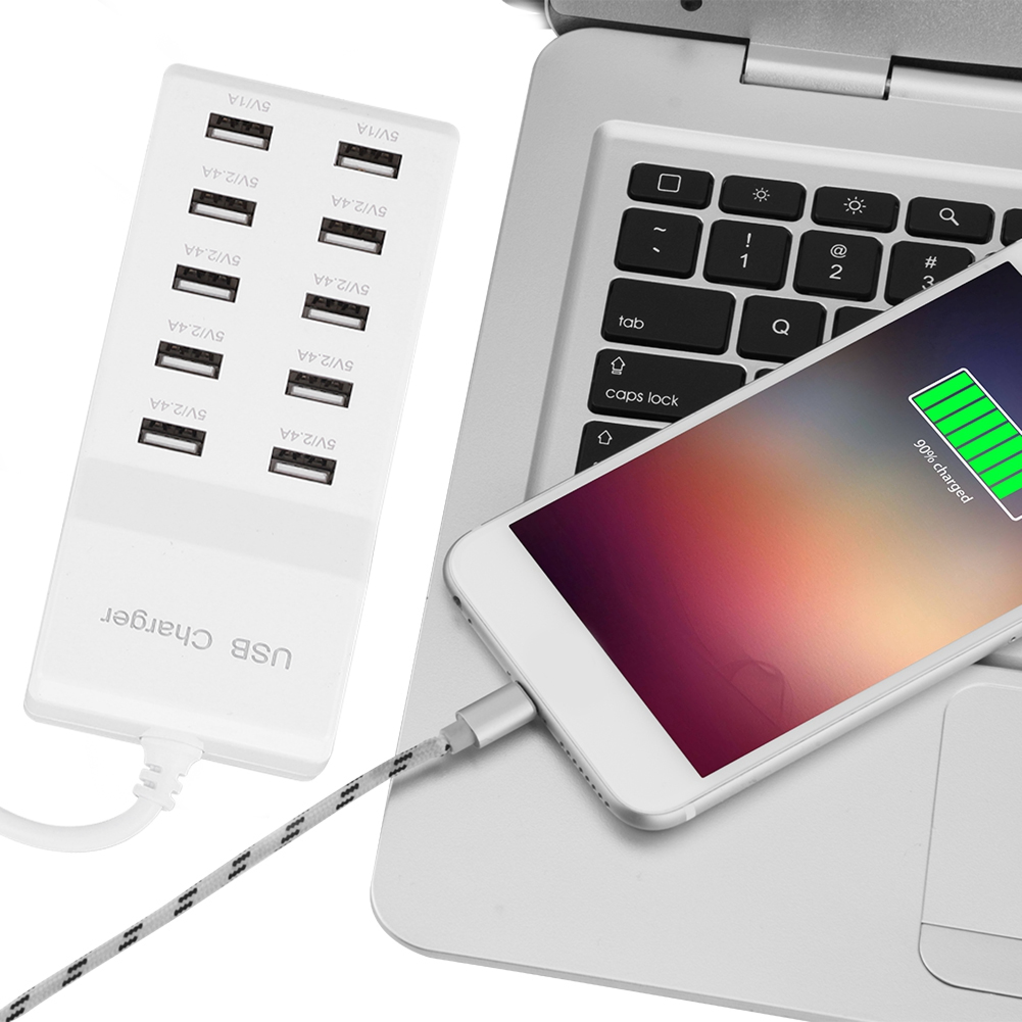 Ein weißes USB-Ladegerät mit mehreren Anschlüssen neben einem Laptop mit einem aufgeladenen Telefon.