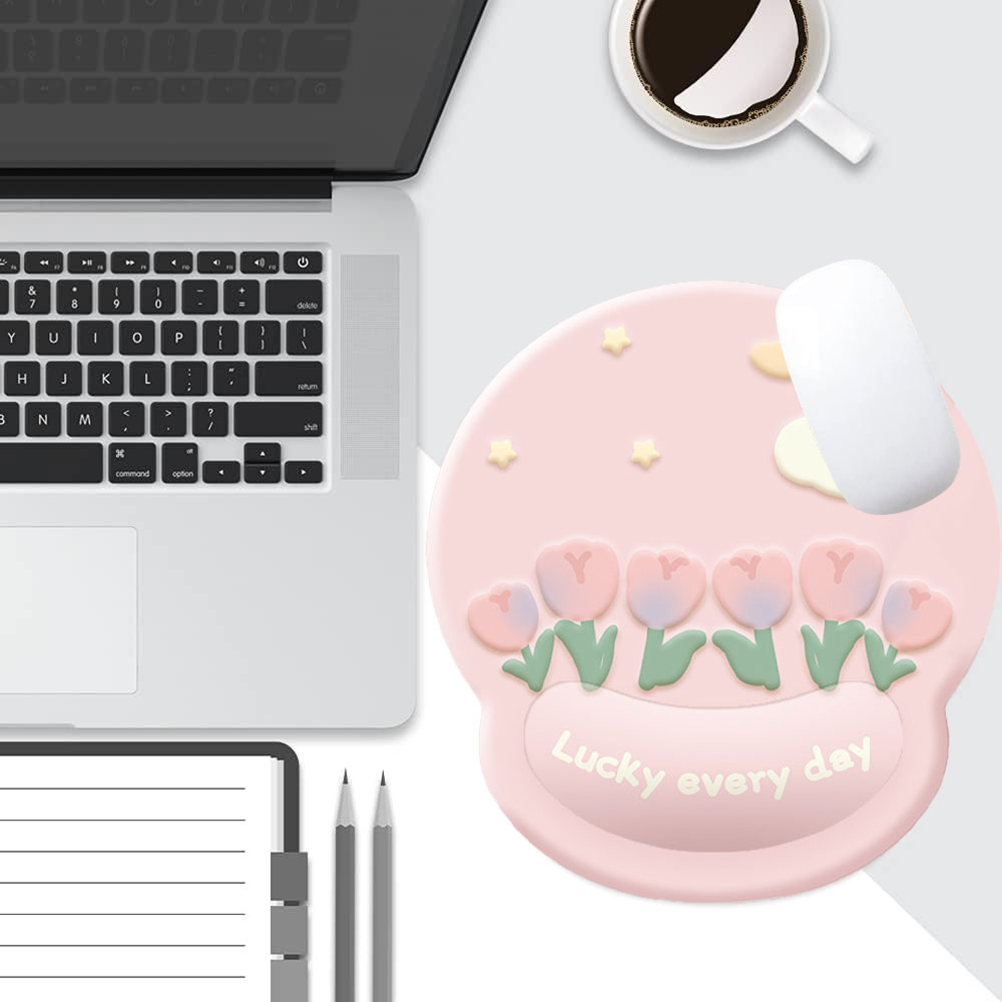 Rosa Mauspad mit Tulpen, Sternen und Wolken, neben einem Laptop und Kaffee.