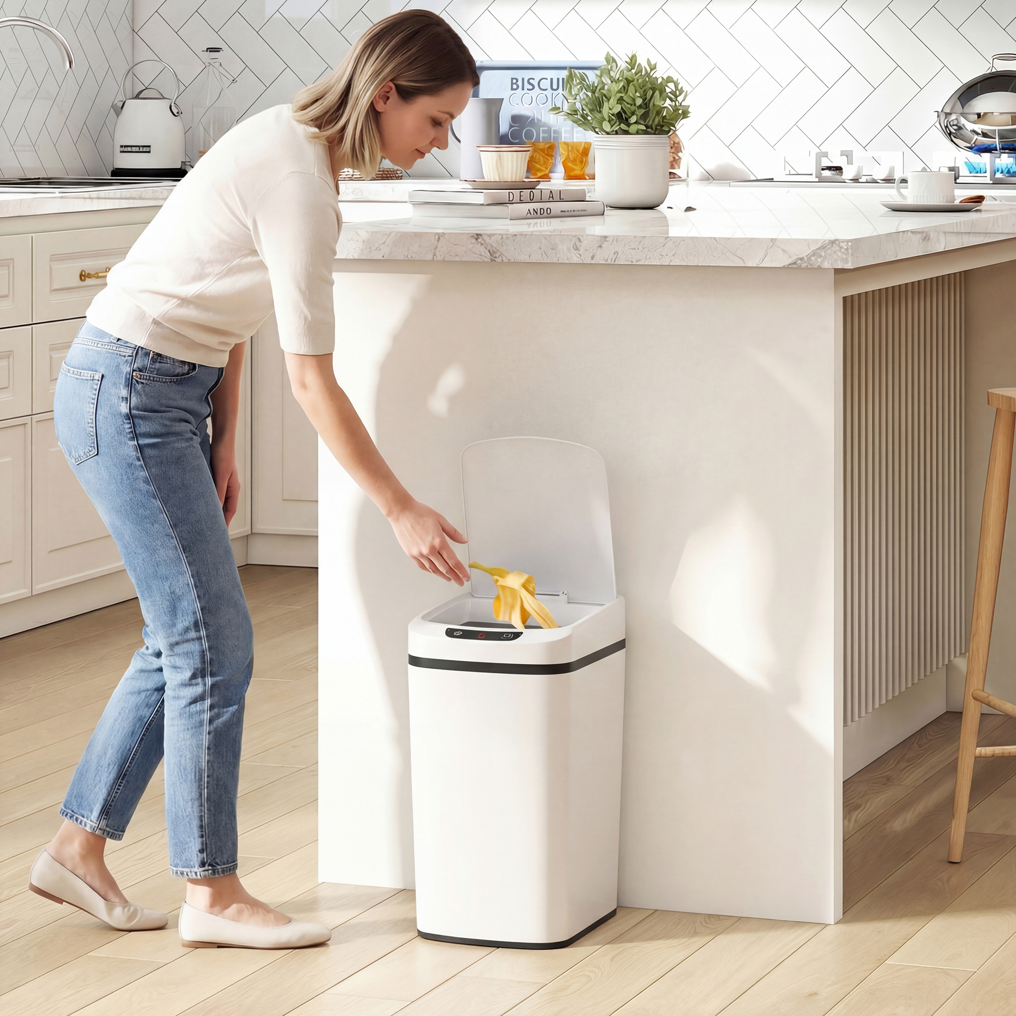 Donna in jeans getta buccia di banana in un cestino automatico bianco in una cucina moderna.