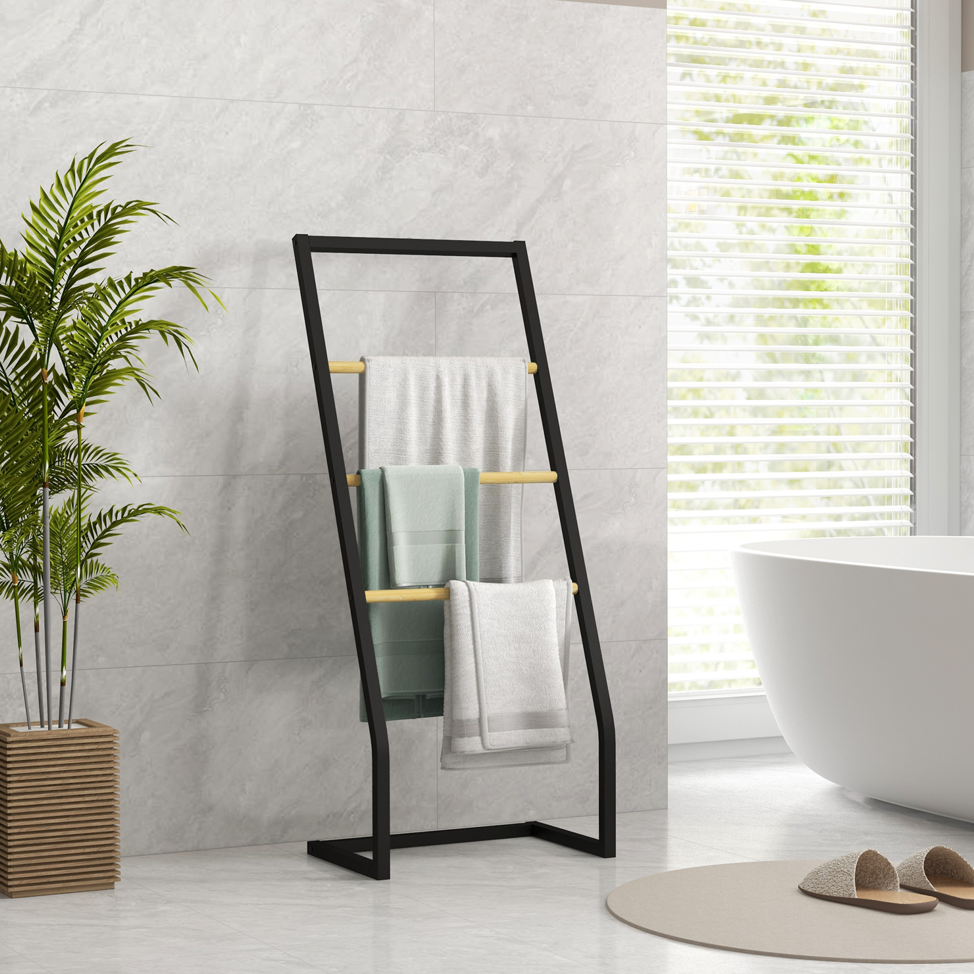 Un porta asciugamani nero con asciugamani si trova accanto a una pianta in un bagno.