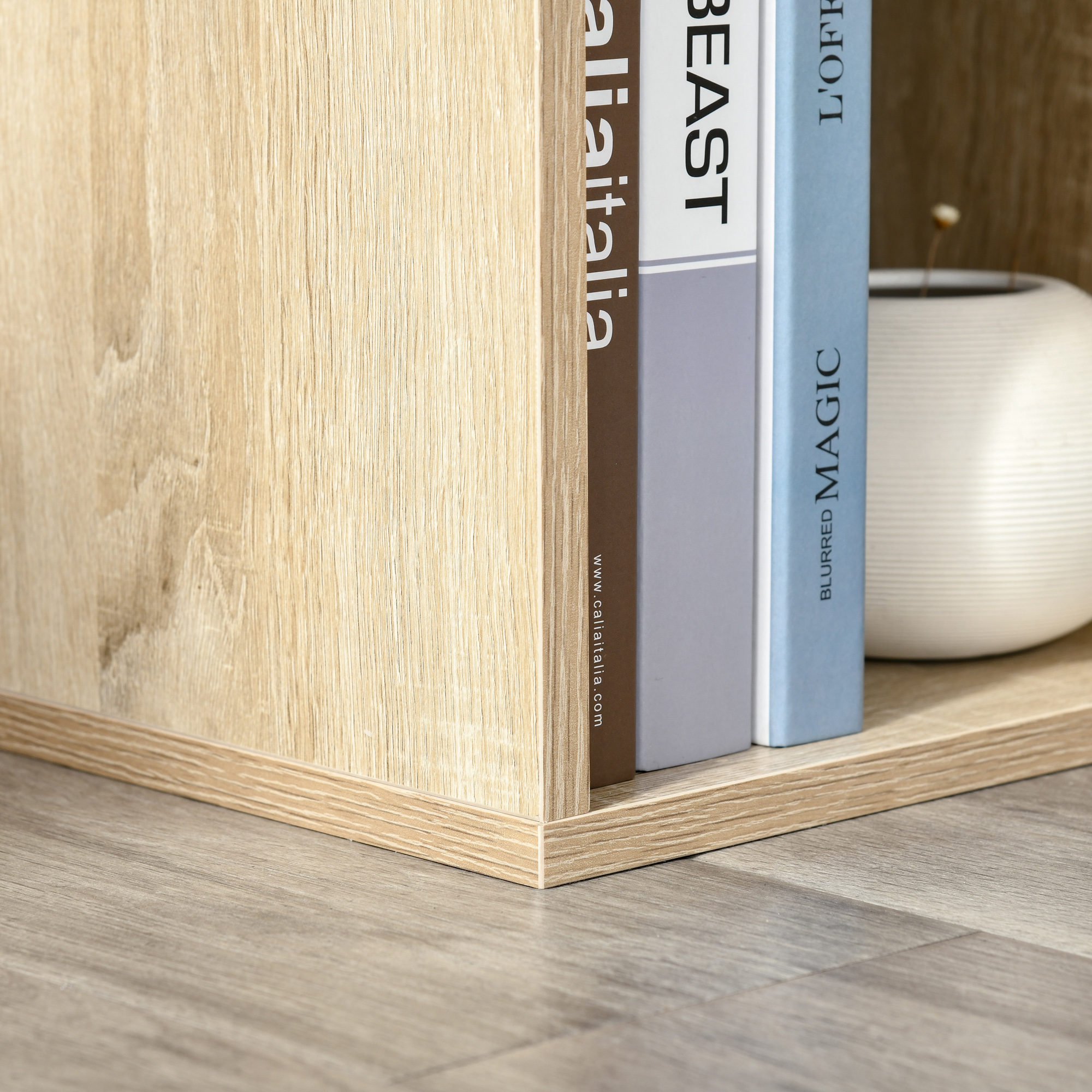 Scaffale con libri e vaso su pavimento in legno.
