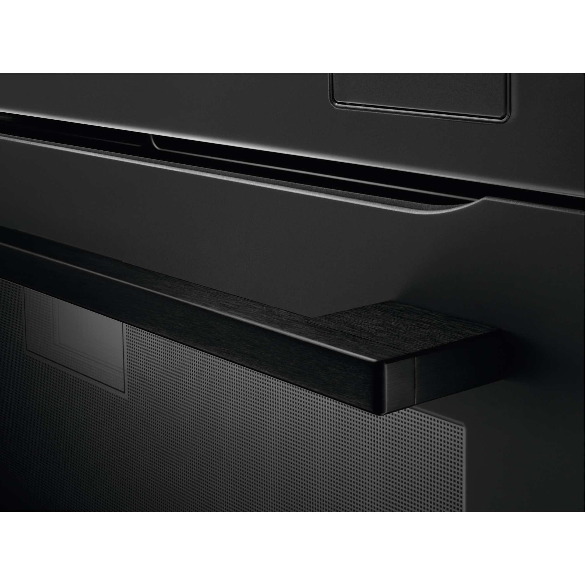 Primer plano de un asa de horno negra con veta de madera sobre una rejilla perforada.