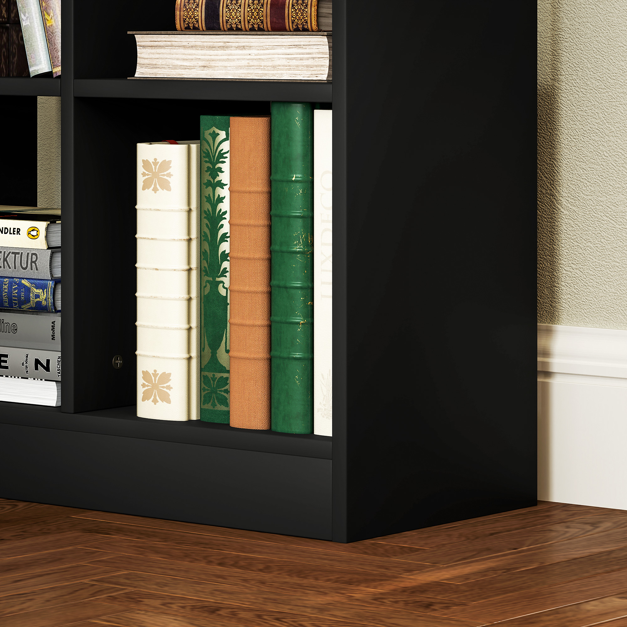 Una libreria nera con libri di vari colori e dimensioni, su un pavimento in legno.