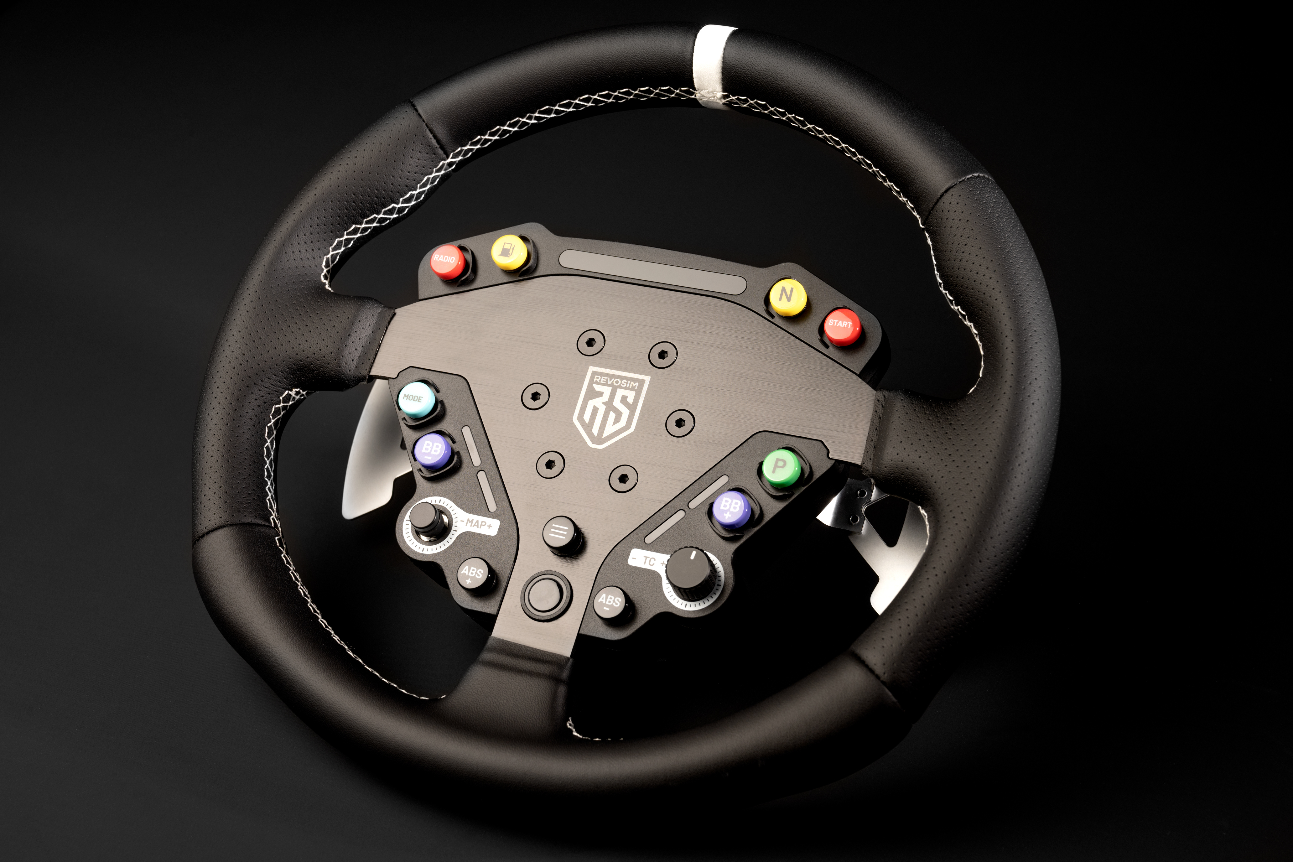 Un volante negro con botones rojos, amarillos y azules sobre fondo negro.