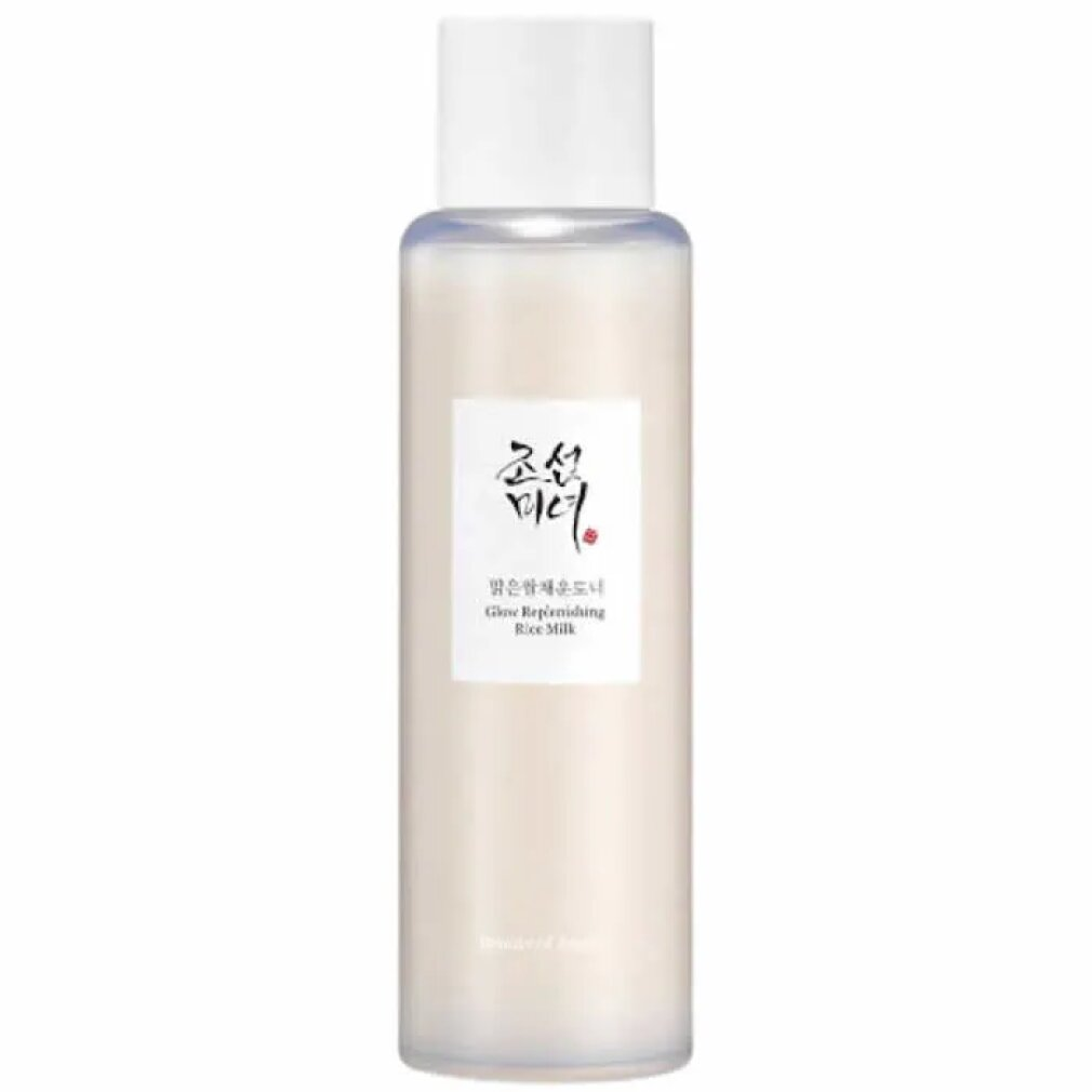 Eine hohe, schlanke Flasche mit blassbeige Flüssigkeit, beschriftet mit Glow Replenishing Rice Milk.
