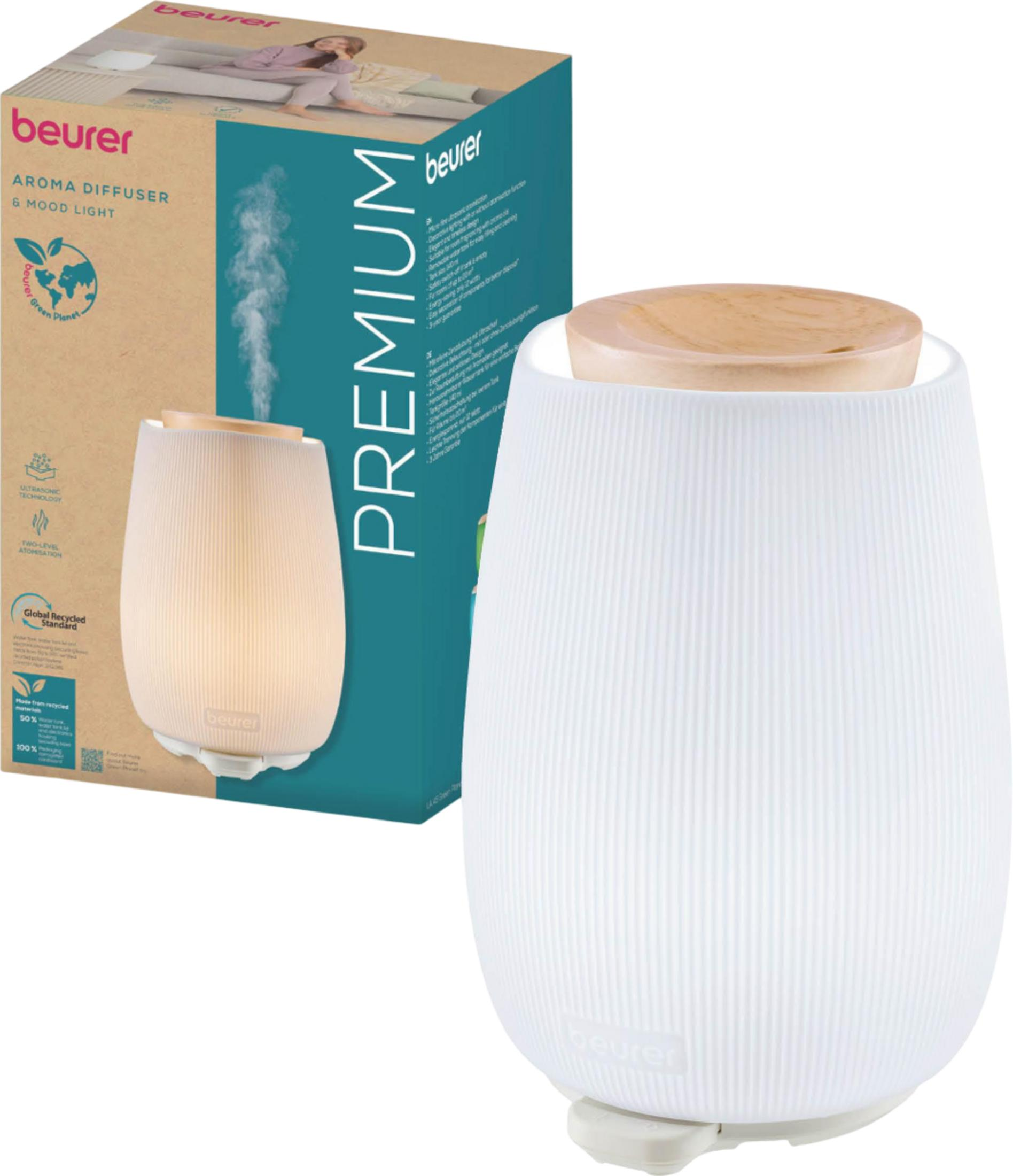 Ein weißer Aroma-Diffusor mit Holzdeckel und Verpackung. Nebel steigt auf.