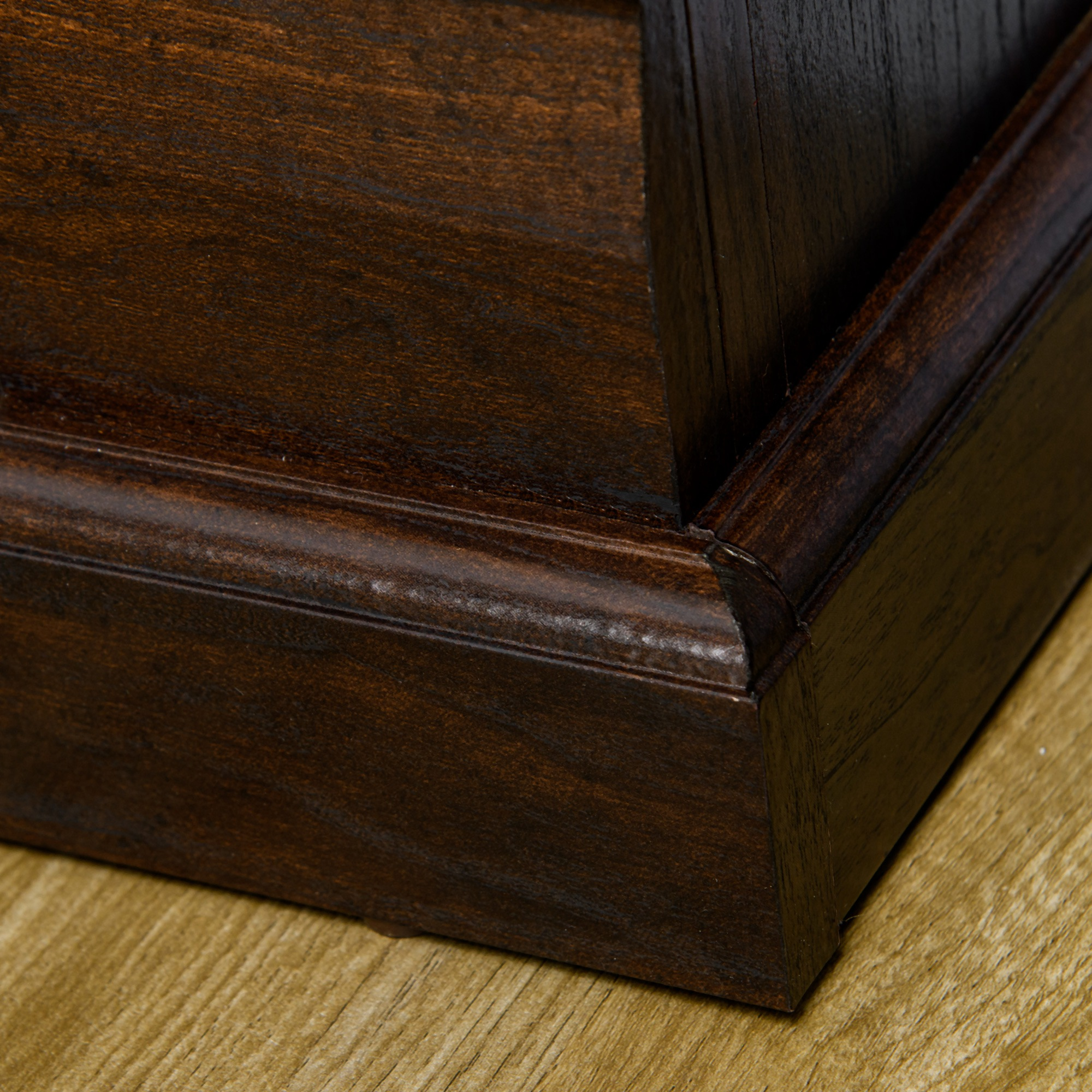 Dettaglio in legno marrone scuro con bordo smussato e venature.