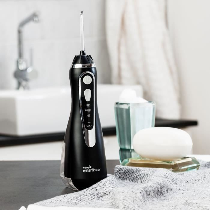 Schwarzer Wasserdruckreiniger mit drei Einstellungen, neben Seife und Glas im Badezimmer.