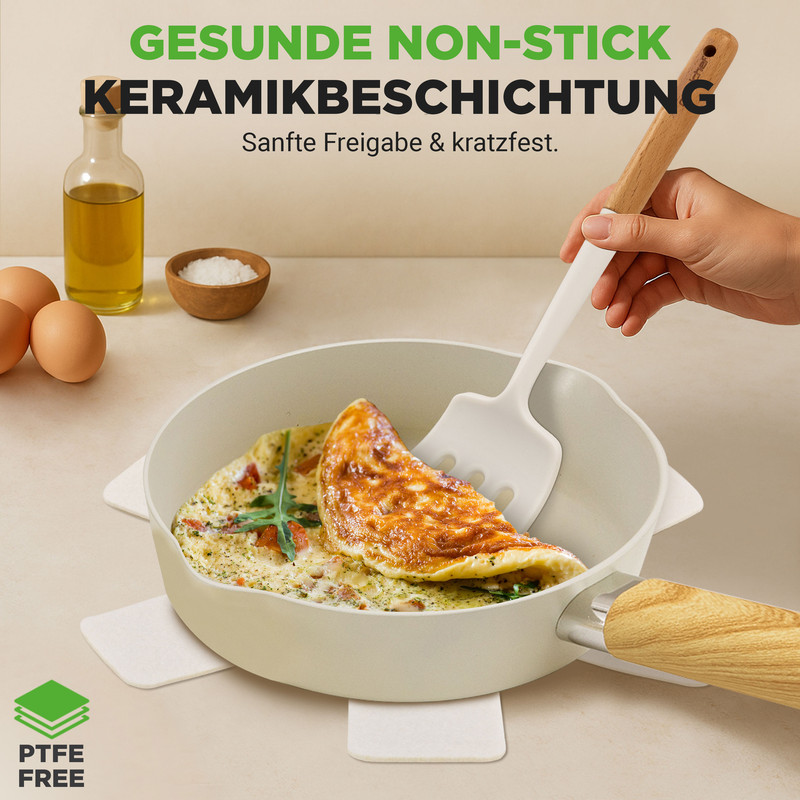 Ein Omelett wird in einer hellen Pfanne mit einem Spatel herausgenommen. Eier, Öl und Salz sind daneben.