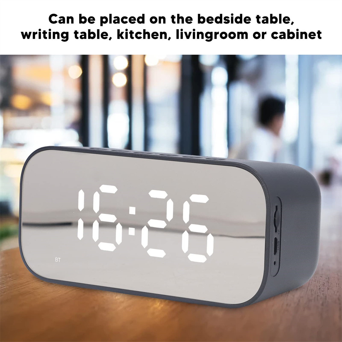 Ein digitaler Wecker mit Spiegel und heller Anzeige auf einem Holztisch.