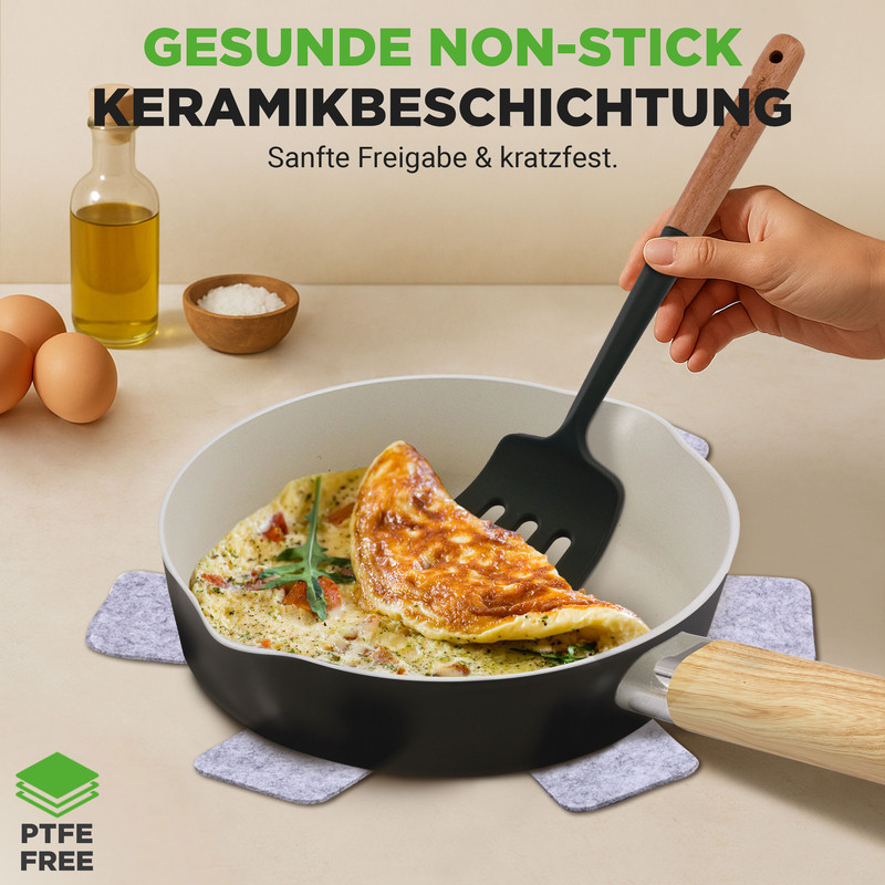 Ein Omelett wird in einer Keramikpfanne mit einem Spatel herausgenommen. Eier, Öl und Salz sind daneben.