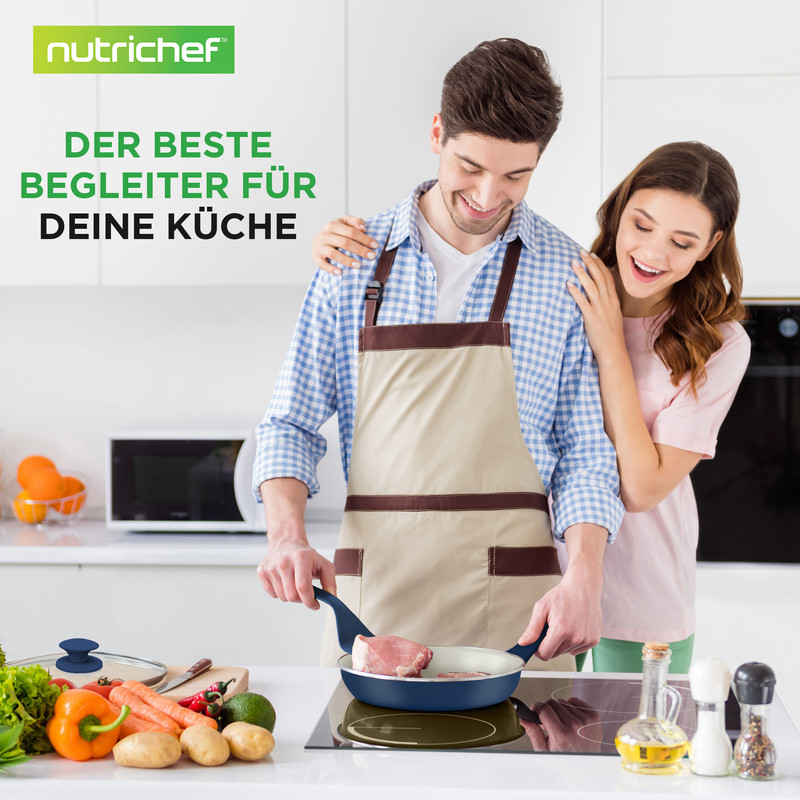 Ein Mann brät Fleisch in einer Pfanne, eine Frau steht hinter ihm.