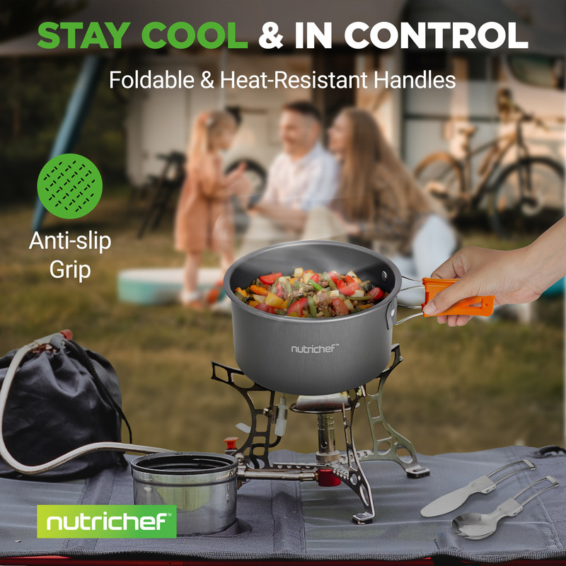 Ein Topf mit Essen kocht auf einem Campingkocher, Familie im Hintergrund.
