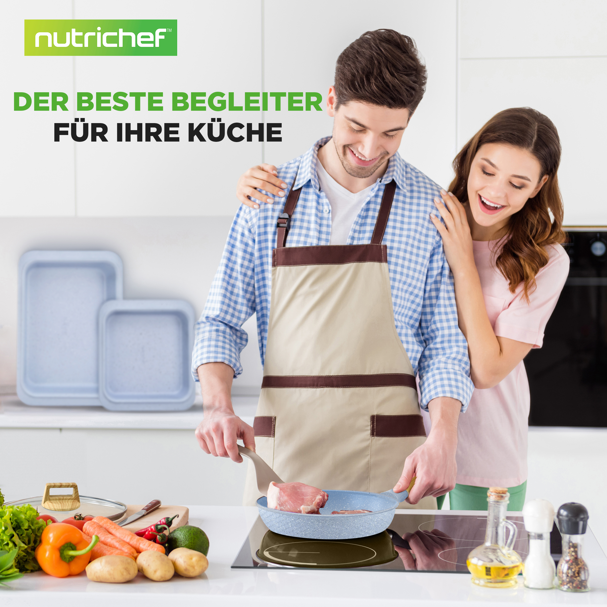 Mann kocht Fleisch in Pfanne, Frau umarmt ihn. Gemüse liegt daneben.