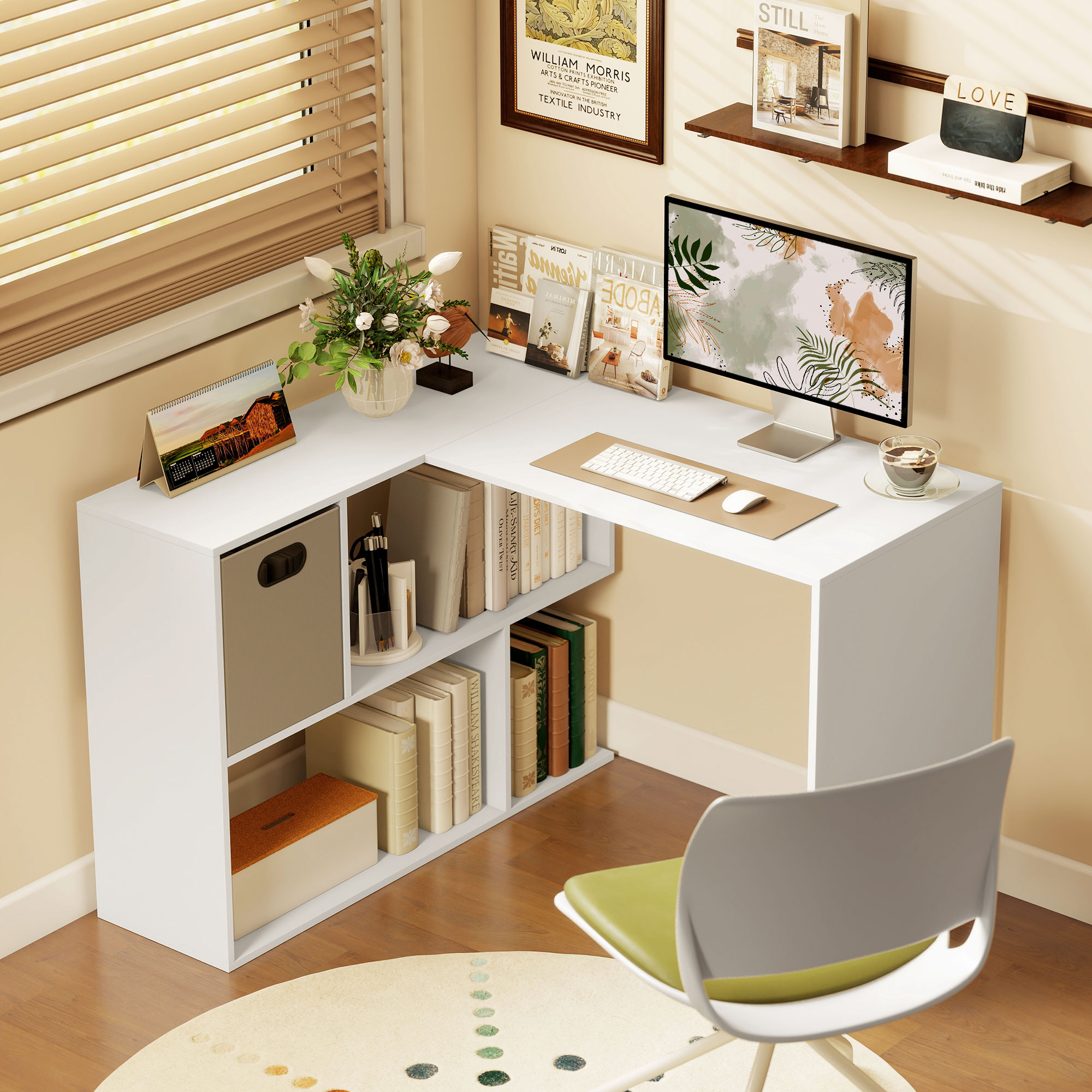 Una scrivania bianca a L con computer, tastiera, mouse, libri e vaso di fiori.