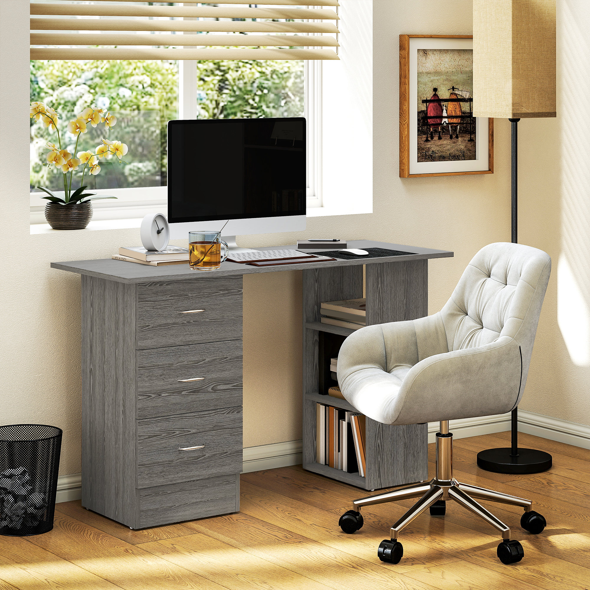 Scrivania grigia con computer, sedia e orchidee gialle vicino a una finestra.