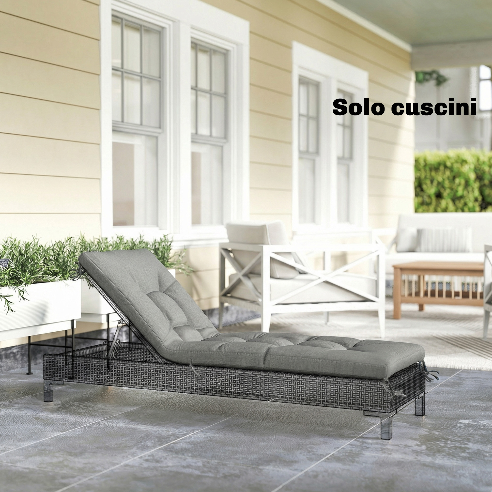 Chaise longue in rattan grigio con cuscini su un patio di fronte a una casa.