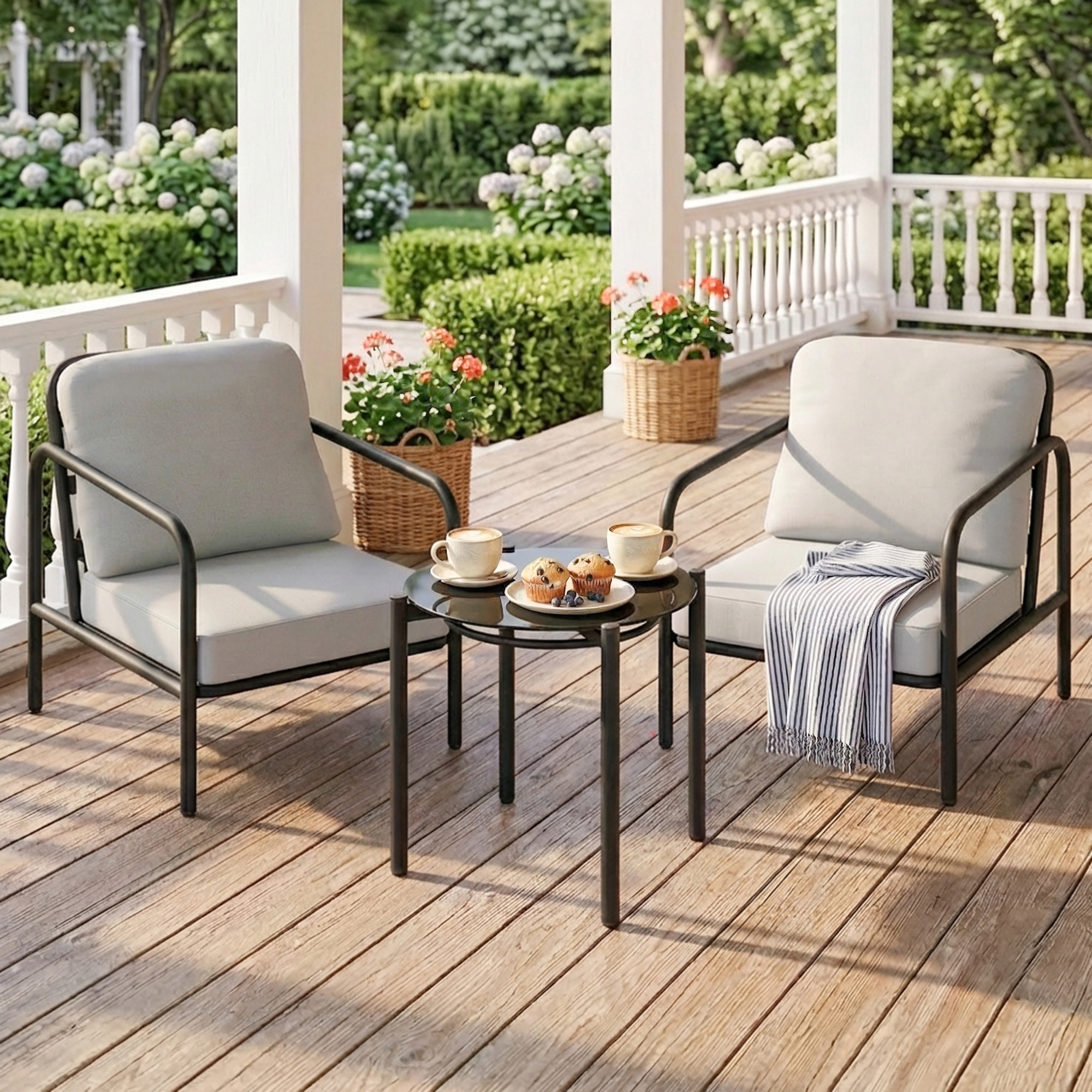 Due poltrone grigie con tavolo su un portico in legno, decorate con fiori e muffin.