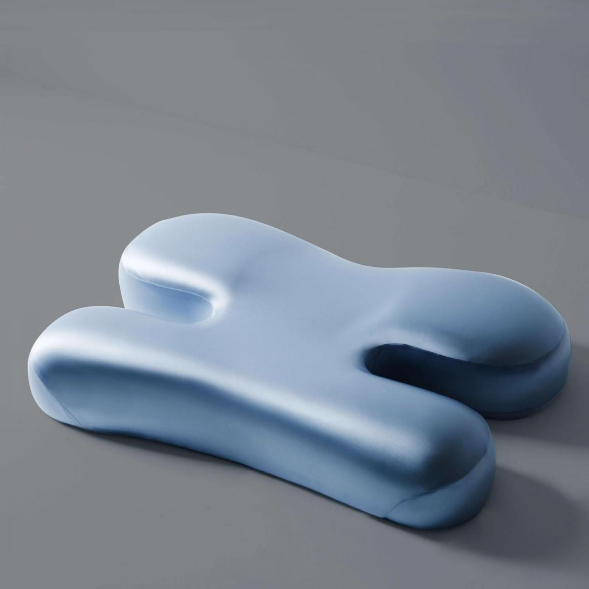 Ein hellblaues, ergonomisches Kissen auf grauem Hintergrund.