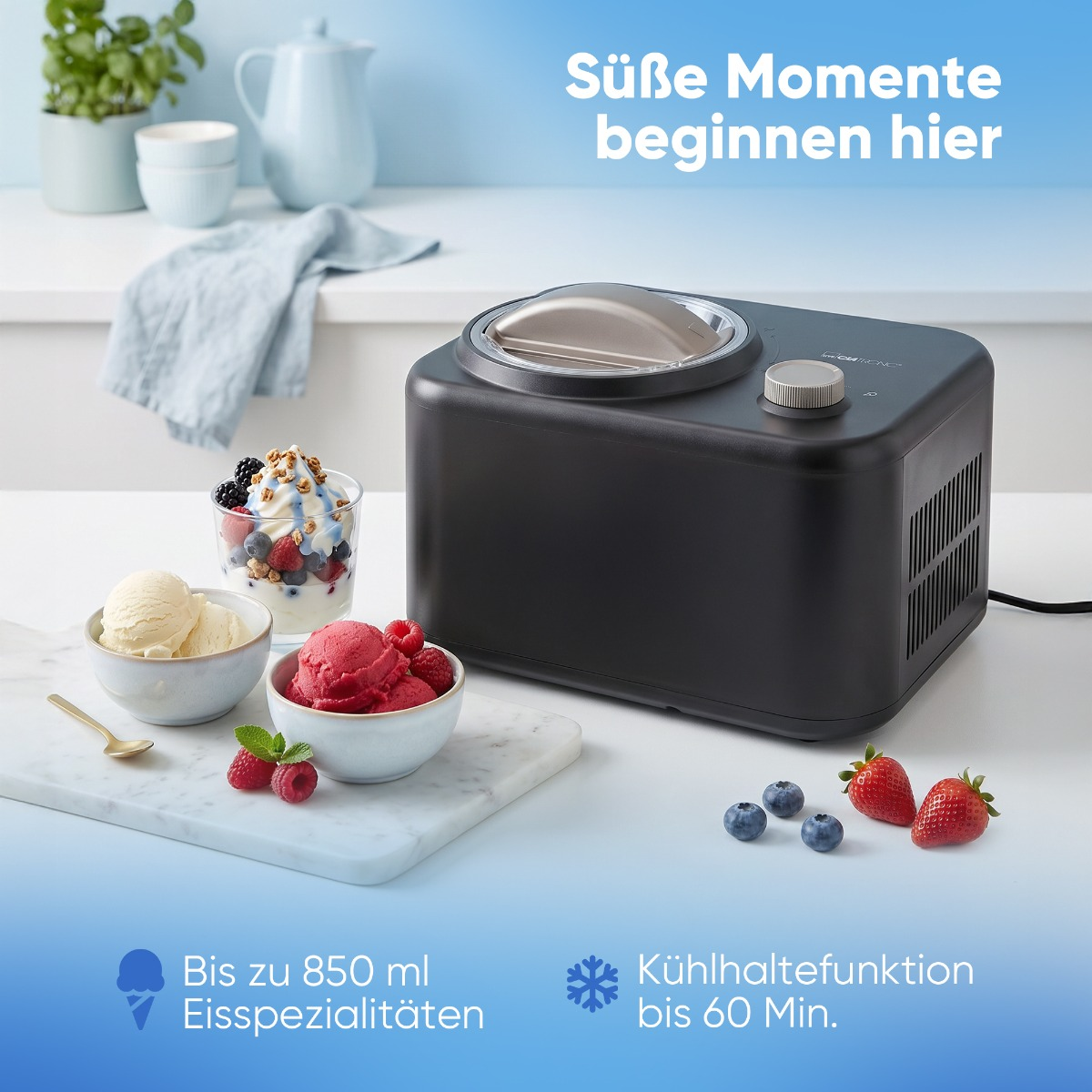 Eismaschine mit Eis und Früchten daneben, auf weißem Tisch.