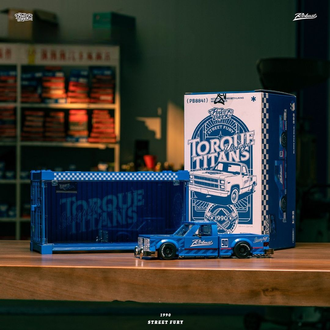 Niebieska ciężarówka-zabawka i kontener z "Torque Titans", obok pudełka.