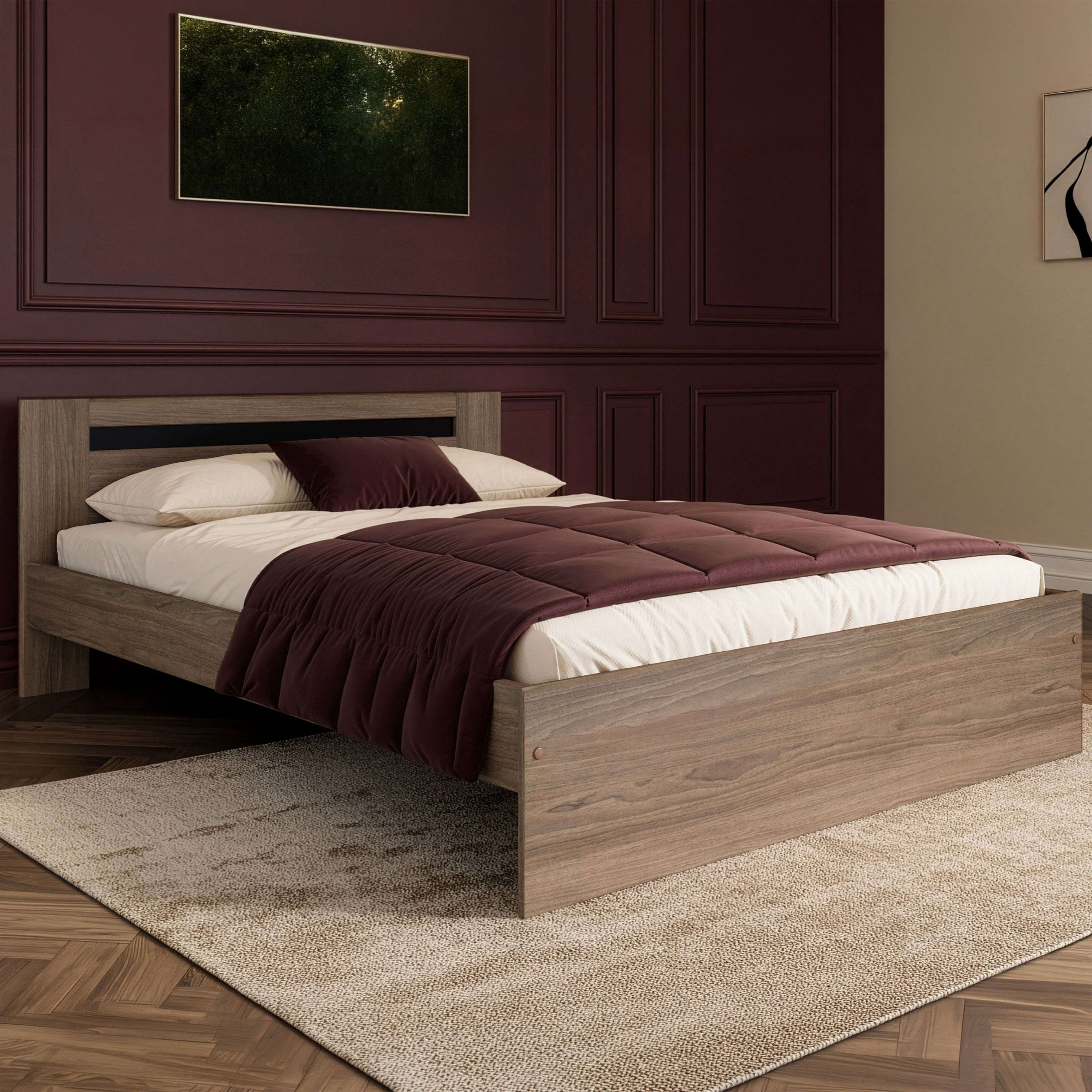 Una cama moderna de madera con almohadas blancas y burdeos, sobre una alfombra.