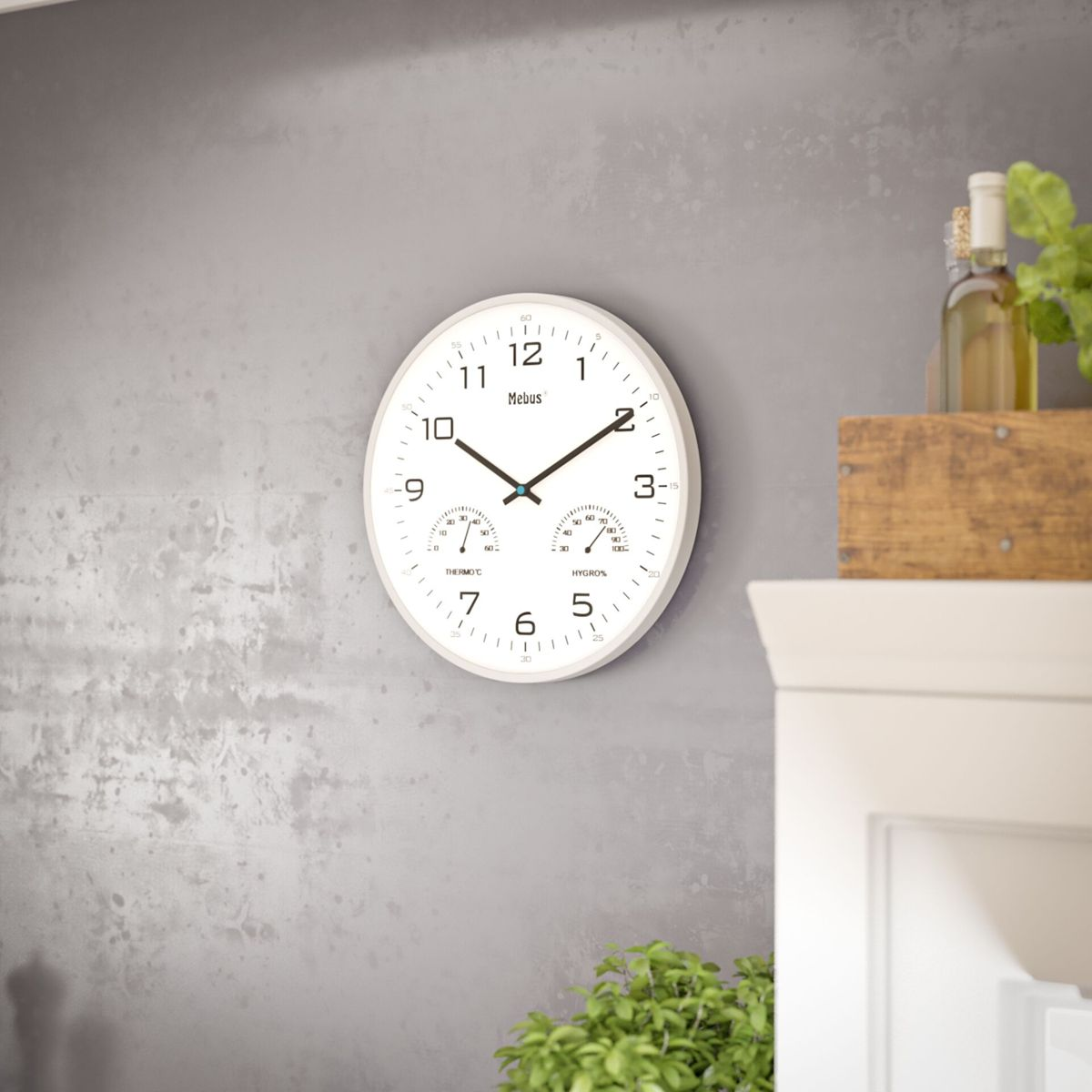 Weiße Wanduhr mit Thermometer und Hygrometer an Betonwand.