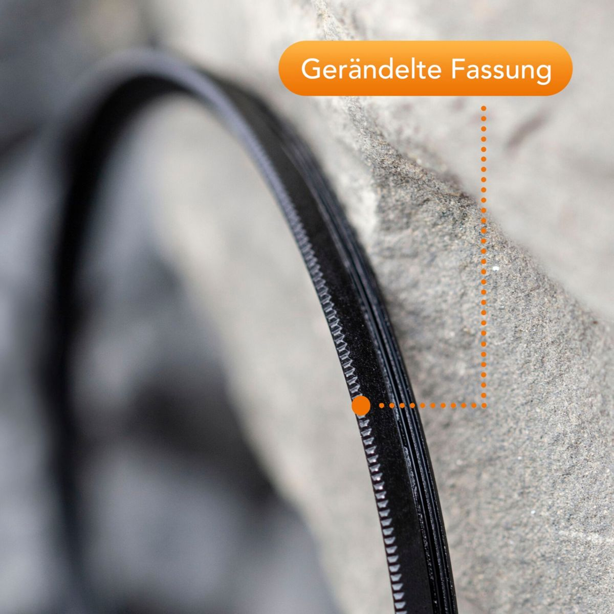 Nahaufnahme eines Reißverschlusses mit gerändelter Fassung und orangefarbenen Markierungen.