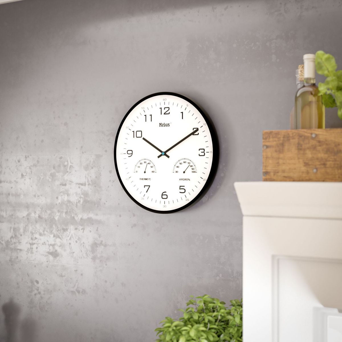 Un orologio da parete bianco con termometro e igrometro è appeso a un muro grigio.