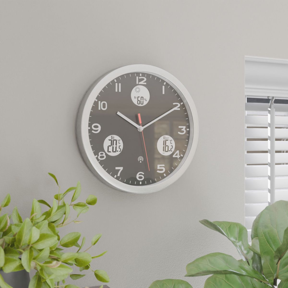 Eine graue Wanduhr mit digitalen Anzeigen für Temperatur und Luftfeuchtigkeit.