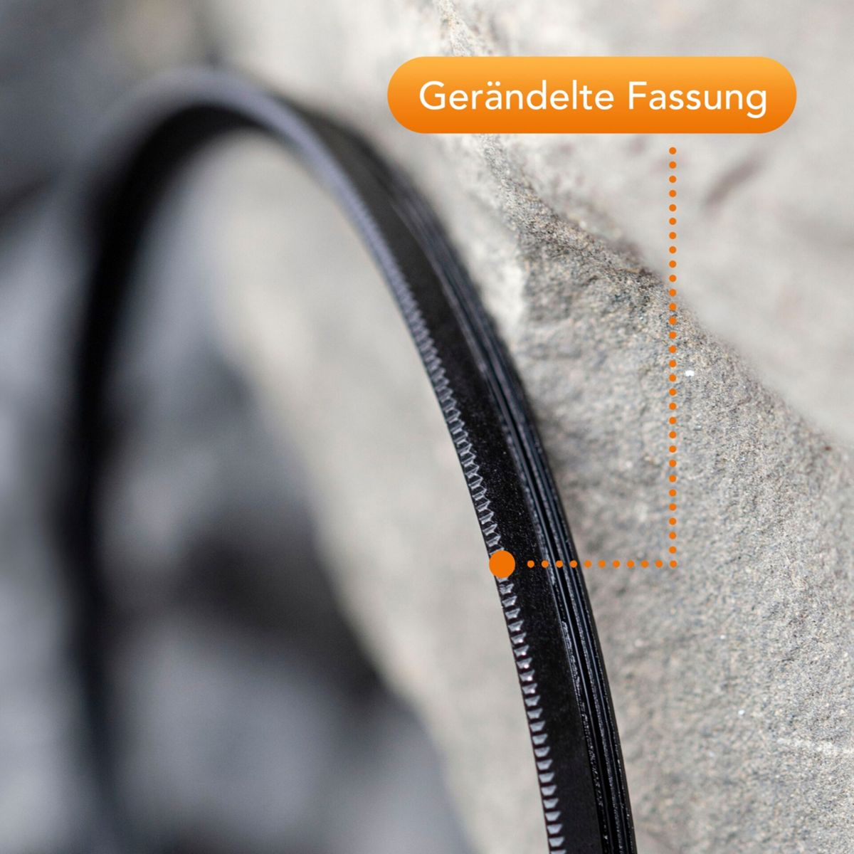 Nahaufnahme eines schwarzen Reißverschlusses mit strukturierter Grifffläche neben einer grauen Textur.