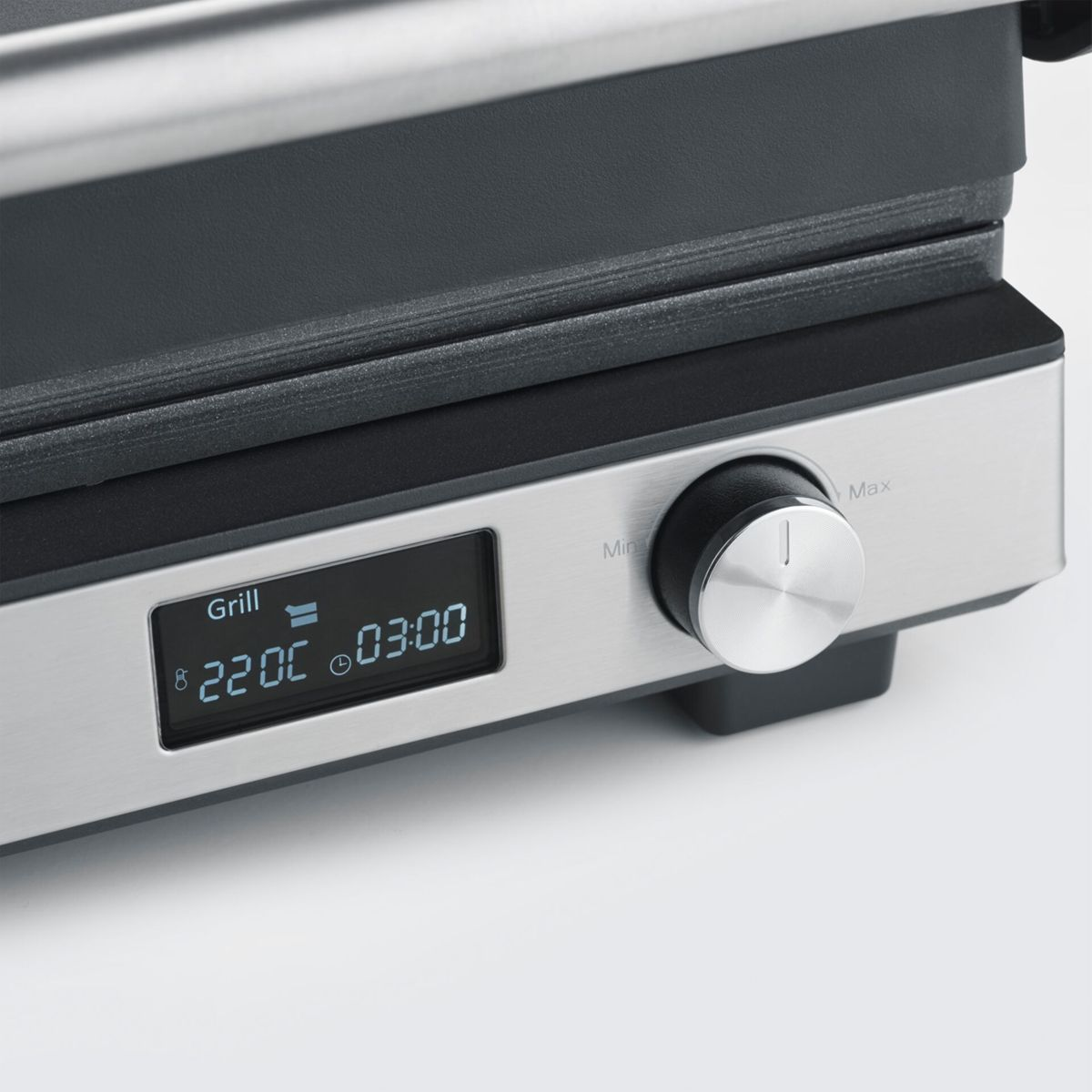 Nahaufnahme eines silbernen Grills mit digitaler Anzeige, die 220C und 03:00 anzeigt.