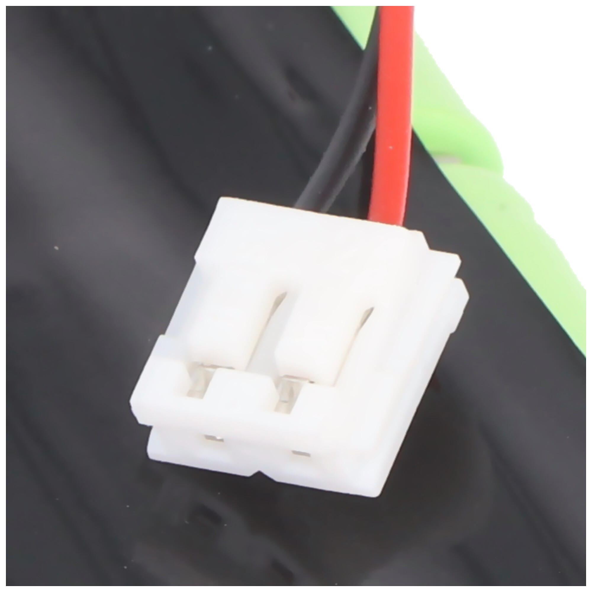 Ein weißer Stecker mit schwarzen und roten Kabeln auf schwarzem Hintergrund.