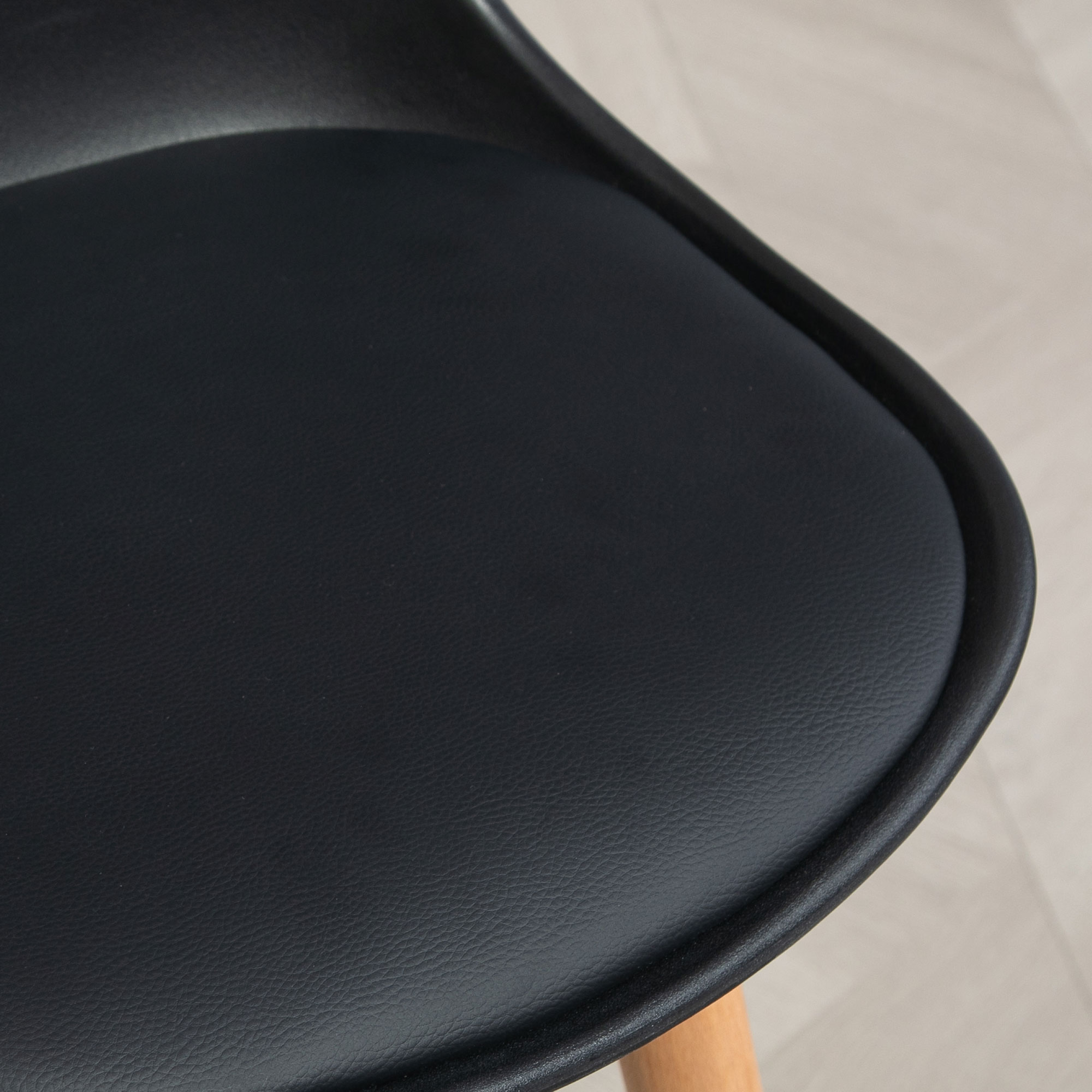Sedile nero di sedia con gamba in legno su pavimento chiaro.