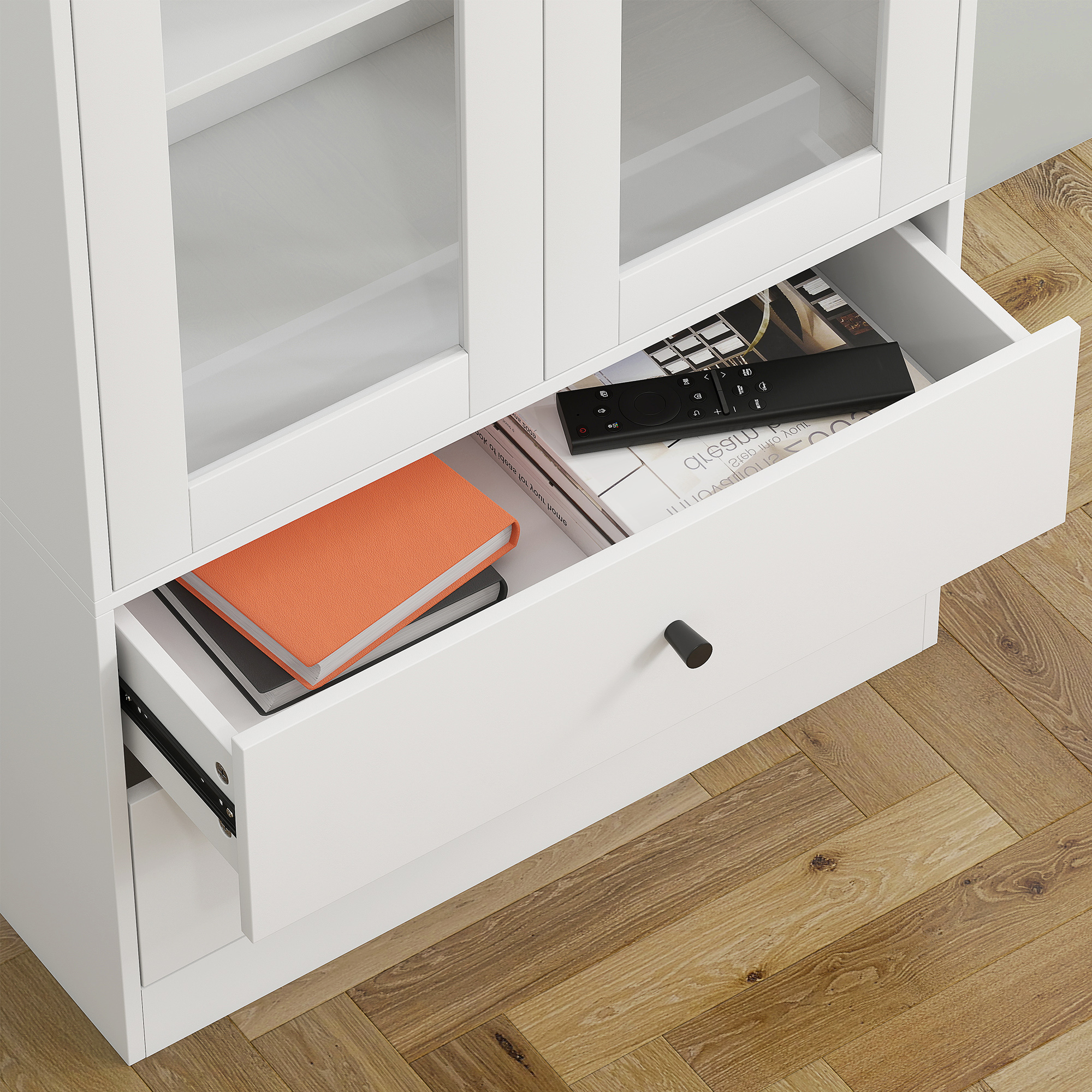 Un armadio bianco con cassetto aperto contenente un libro arancione e un telecomando.