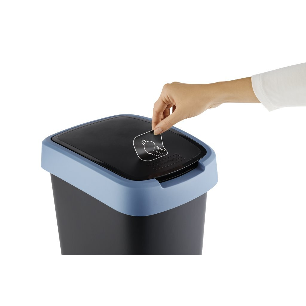 Ręka przykleja symbol recyklingu butelek na czarnym koszu na śmieci z niebieską obwódką.