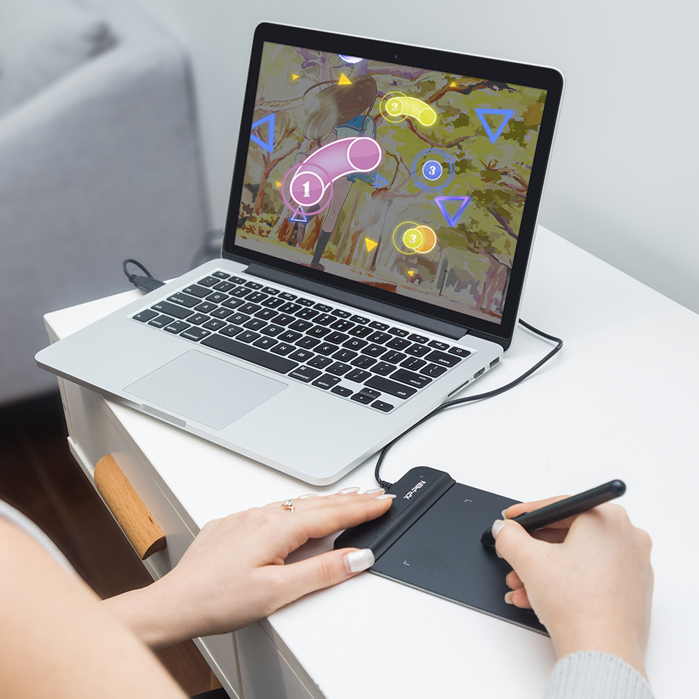 Persona jugando un juego en una laptop usando una tableta gráfica y un lápiz.