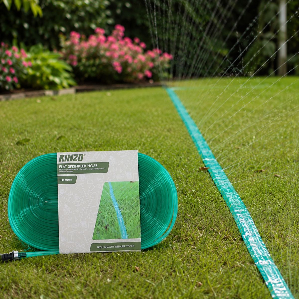 A green Kinzo flat sprinkler hose is coiled on grass, with a sprinkler hose in use in the background.