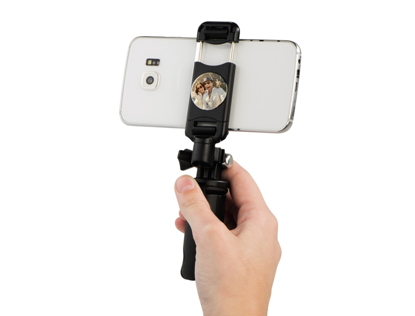 Una mano tiene uno smartphone su un selfie stick con una coppia sullo schermo.