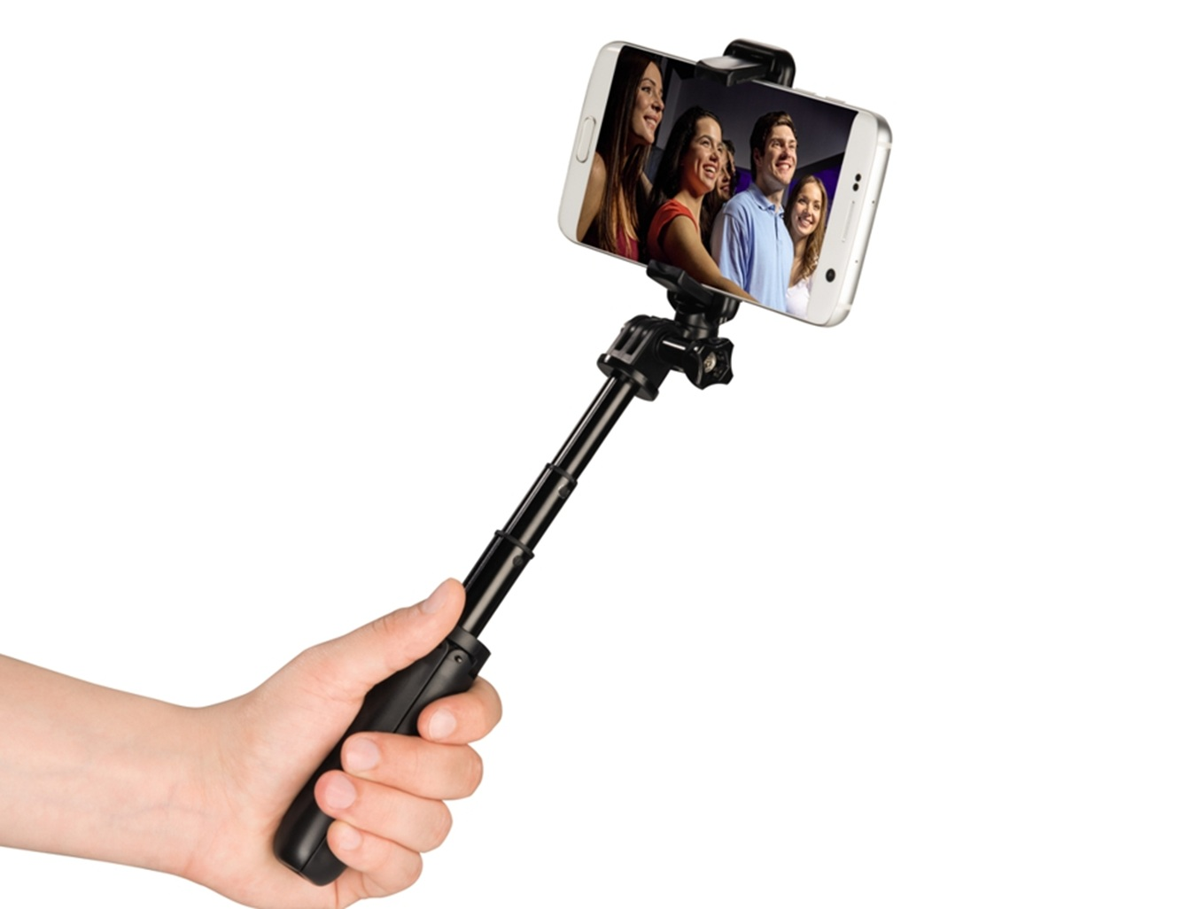 Mano che tiene selfie stick con smartphone che mostra quattro persone sorridenti.