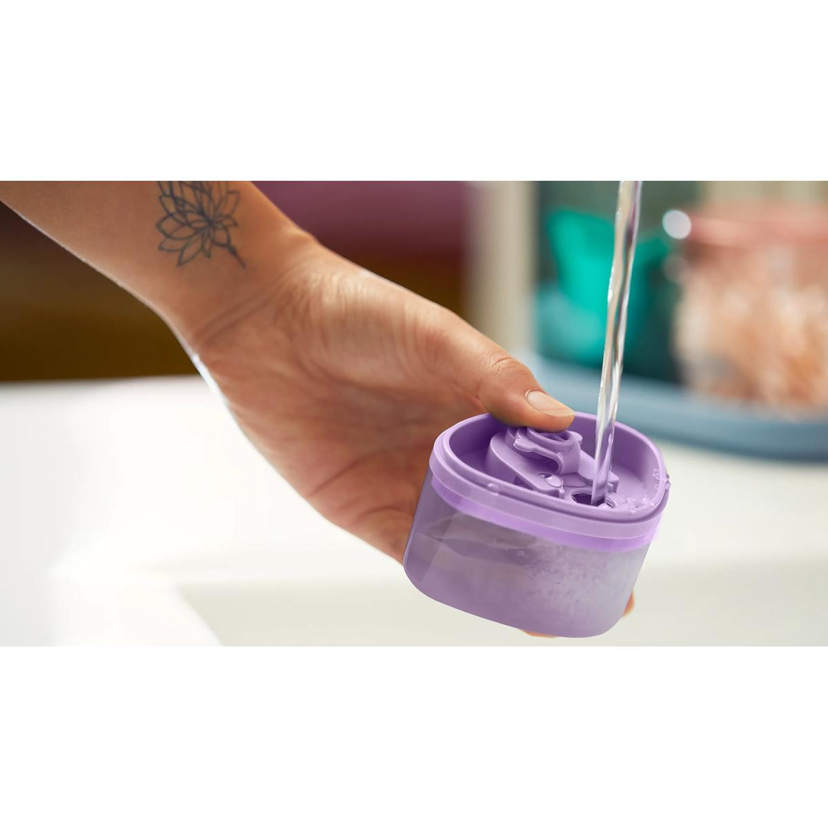 Hand houdt paars bakje onder waterstraal.