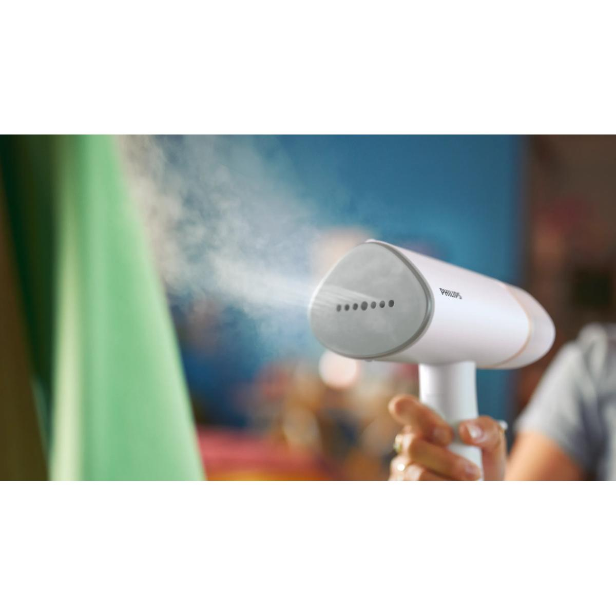 Eine weiße Philips-Dampfbürste sprüht Dampf auf ein grünes Kleidungsstück.