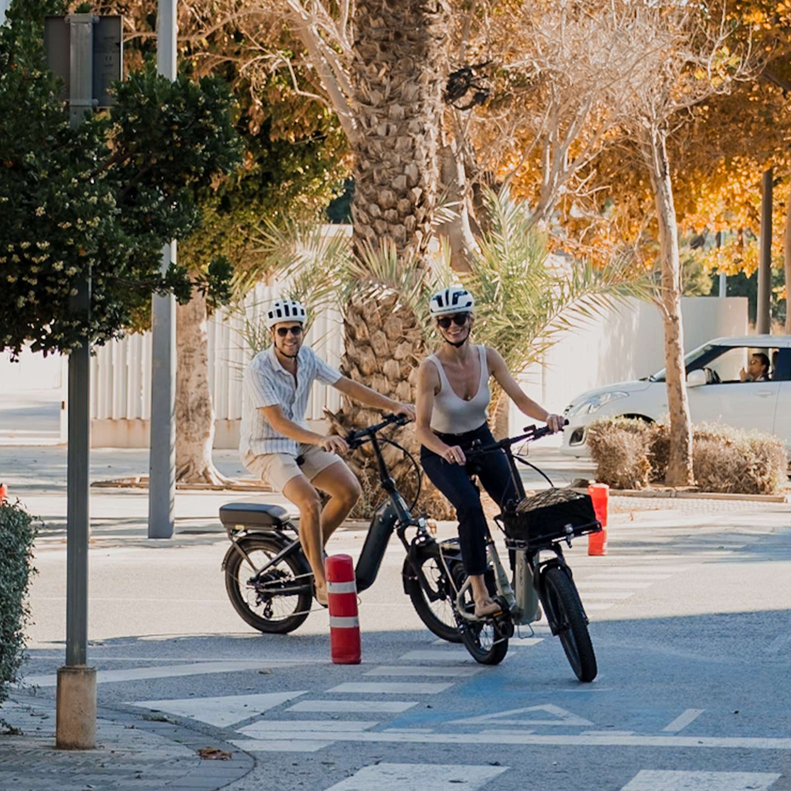 Ein Mann und eine Frau fahren nebeneinander auf E-Bikes auf einer Straße.