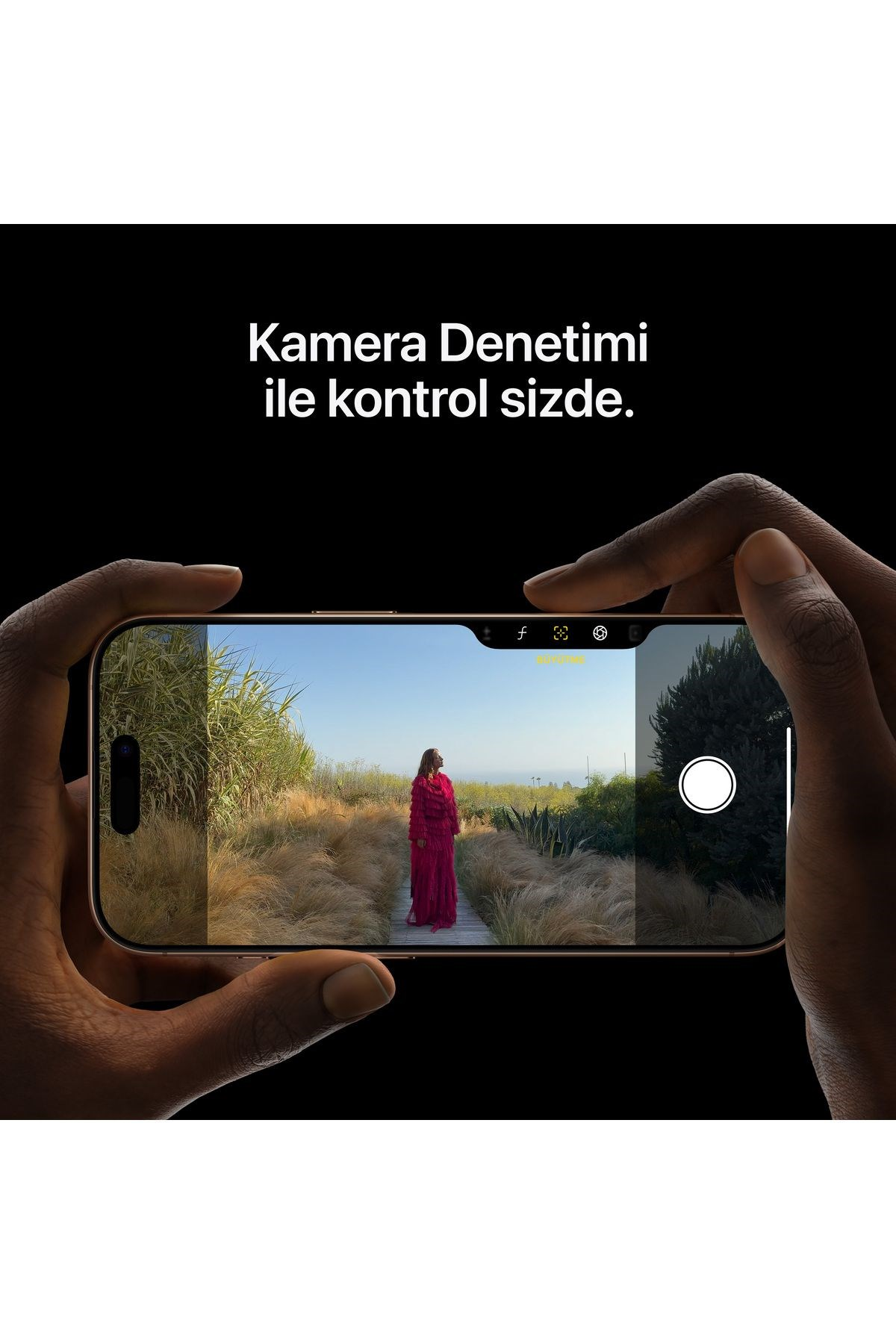 Kırmızı elbiseli bir kadın, çimenli bir alanda tahta bir yolda duruyor, iPhone ile çekildi.