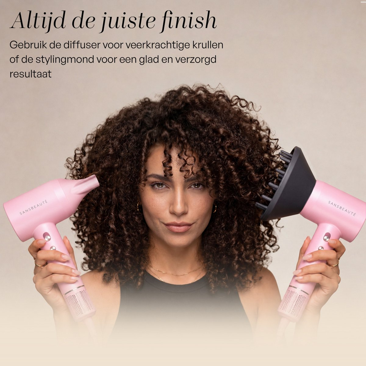 Una donna con capelli ricci tiene due asciugacapelli rosa.